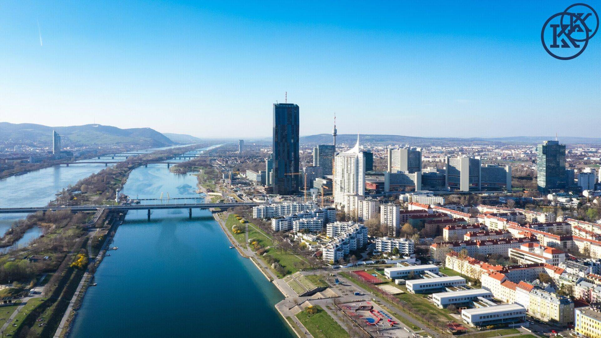 Panoramablick auf die Stadt Wien mit der Donau und modernen Hochhäusern.
