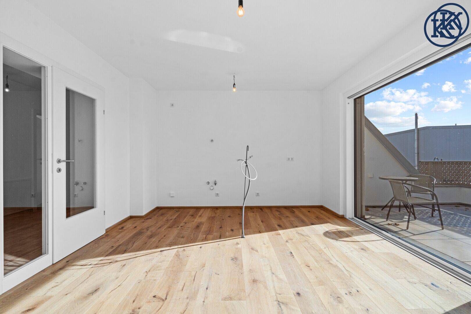 Lichtdurchfluteter Raum mit Holzboden und Zugang zu einer sonnigen Terrasse.