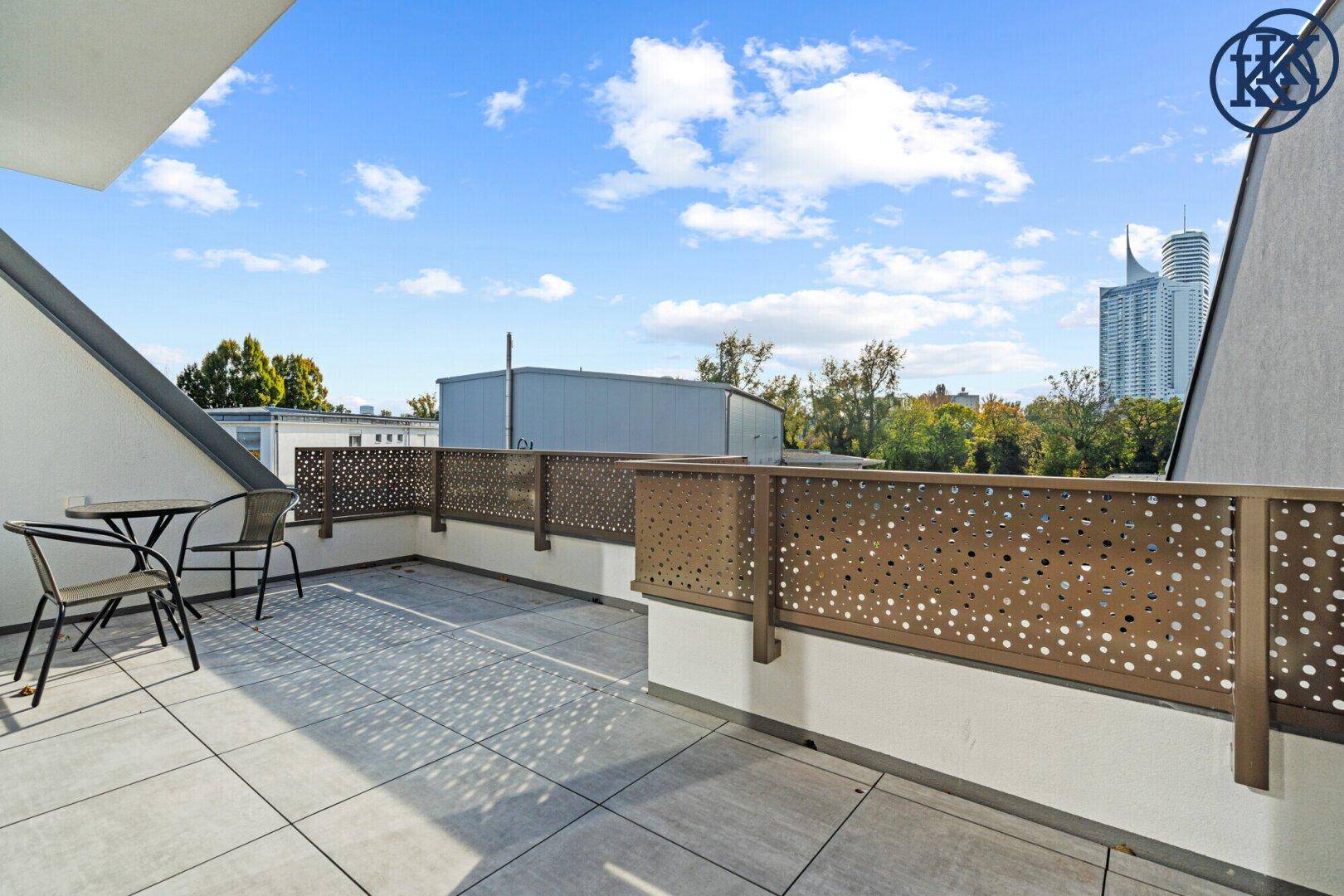 Geräumige Dachterrasse mit Fliesenboden und Blick auf die Stadt und den Himmel.