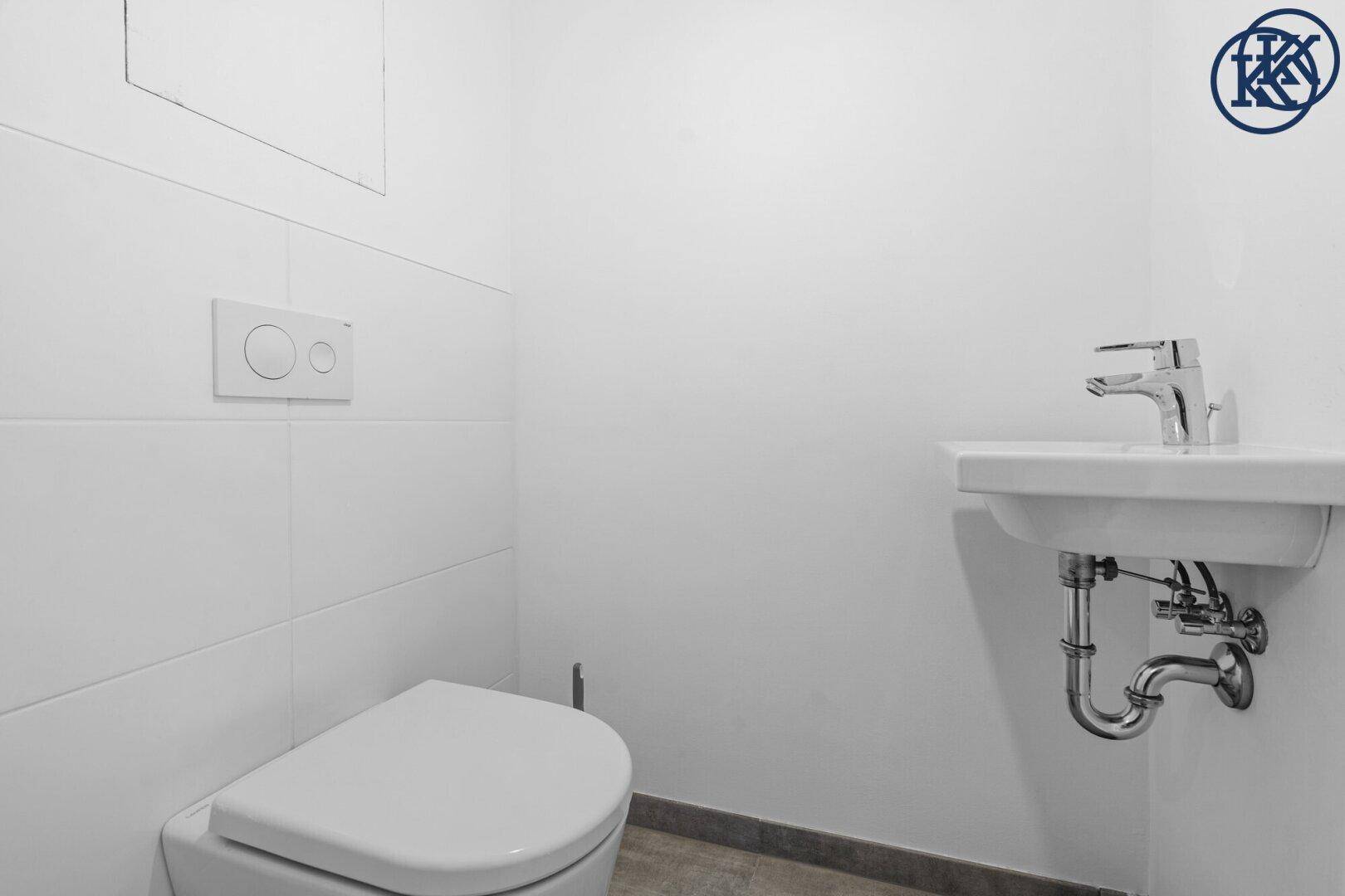 Modernes Gäste-WC mit wandhängender Toilette und kleinem Waschbecken.
