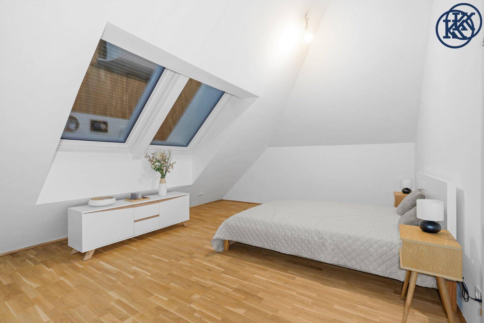 Gemütliches Schlafzimmer mit Holzboden und Dachfenstern, die viel Tageslicht hereinlassen.