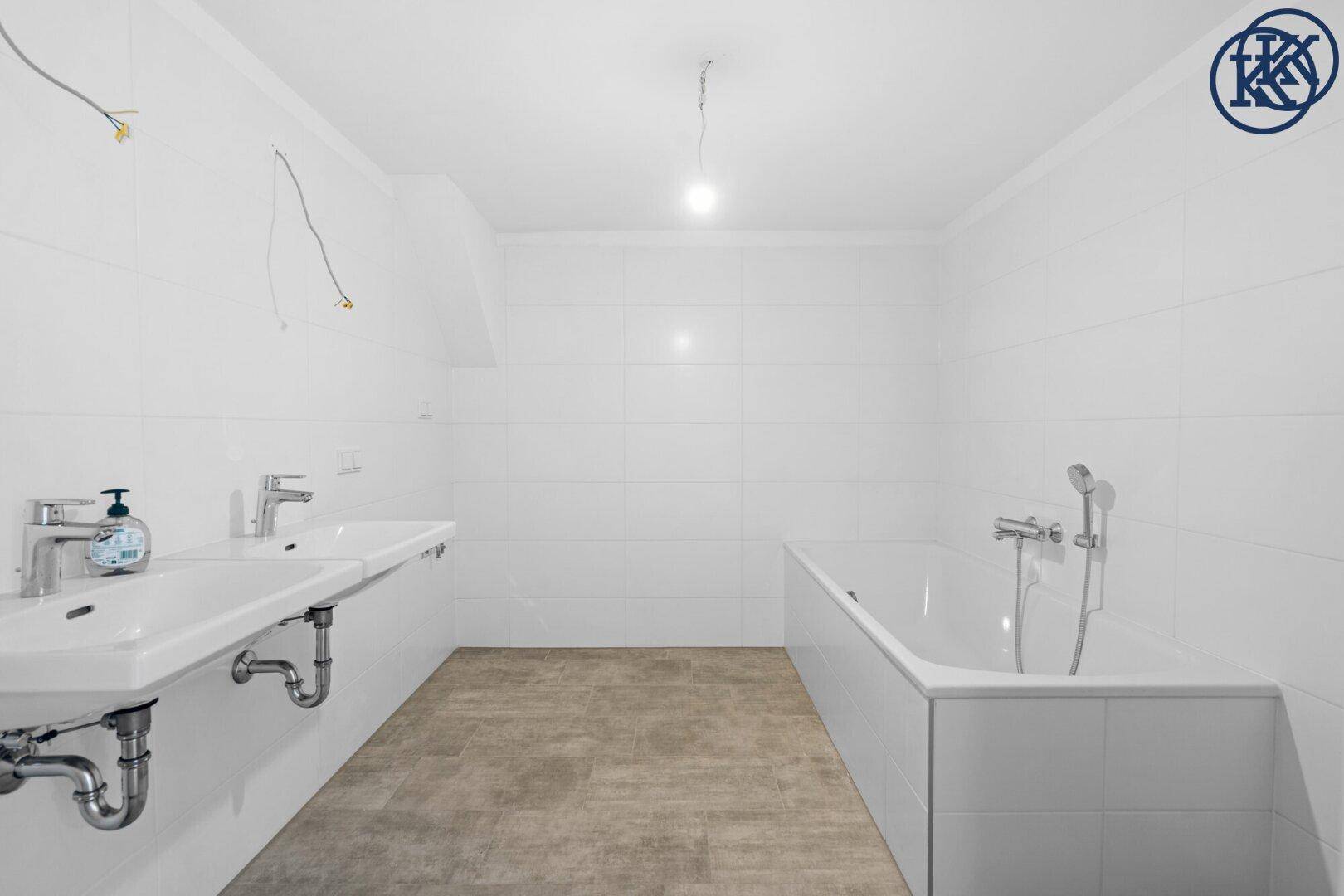 Geräumiges Badezimmer mit zwei Waschbecken und einer Badewanne, noch unfertig.