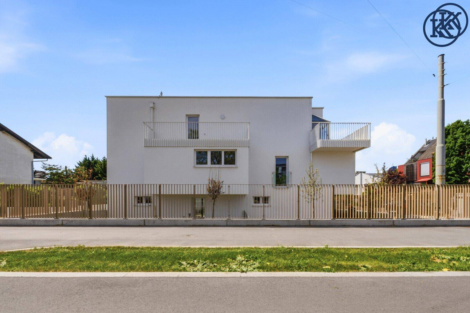 Seitenansicht eines modernen Wohngebäudes mit Balkonen und weißer Fassade.