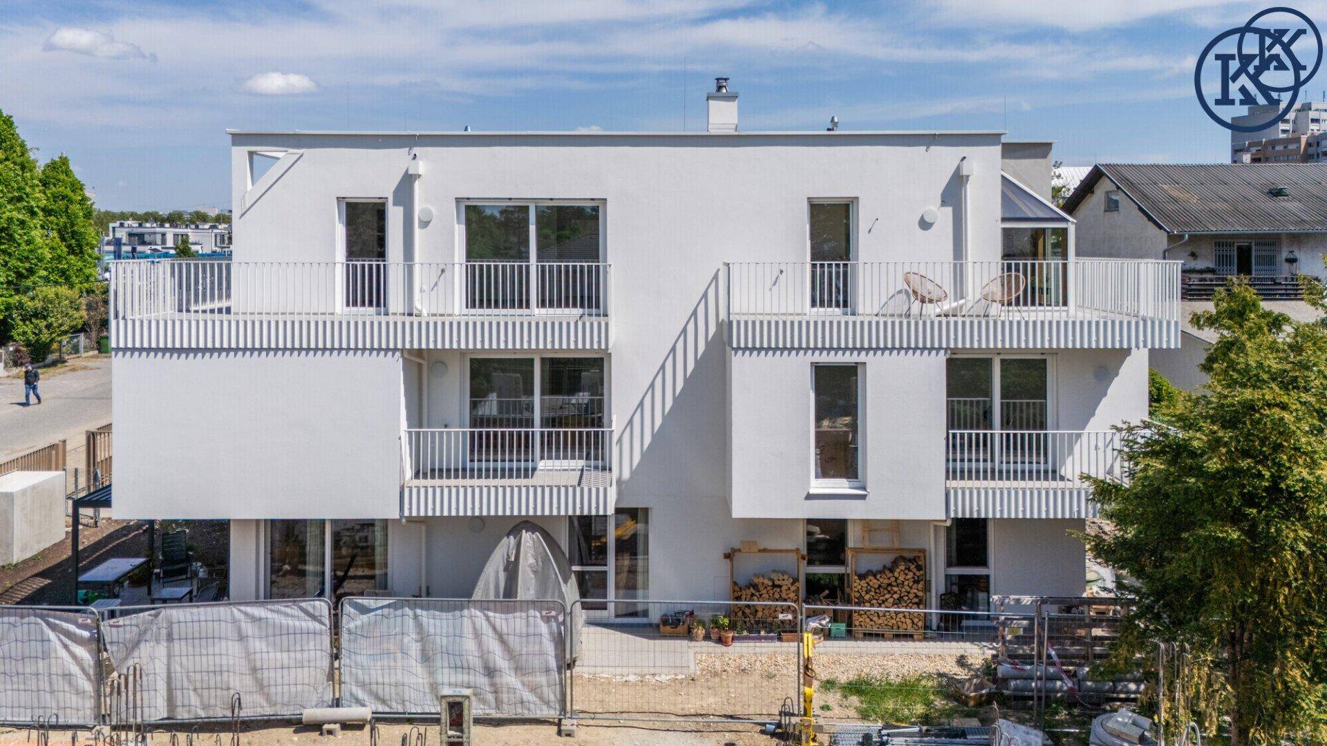 Moderne Wohnanlage mit mehreren Balkonen und großen Fenstern, umgeben von Baustellenabsperrungen.