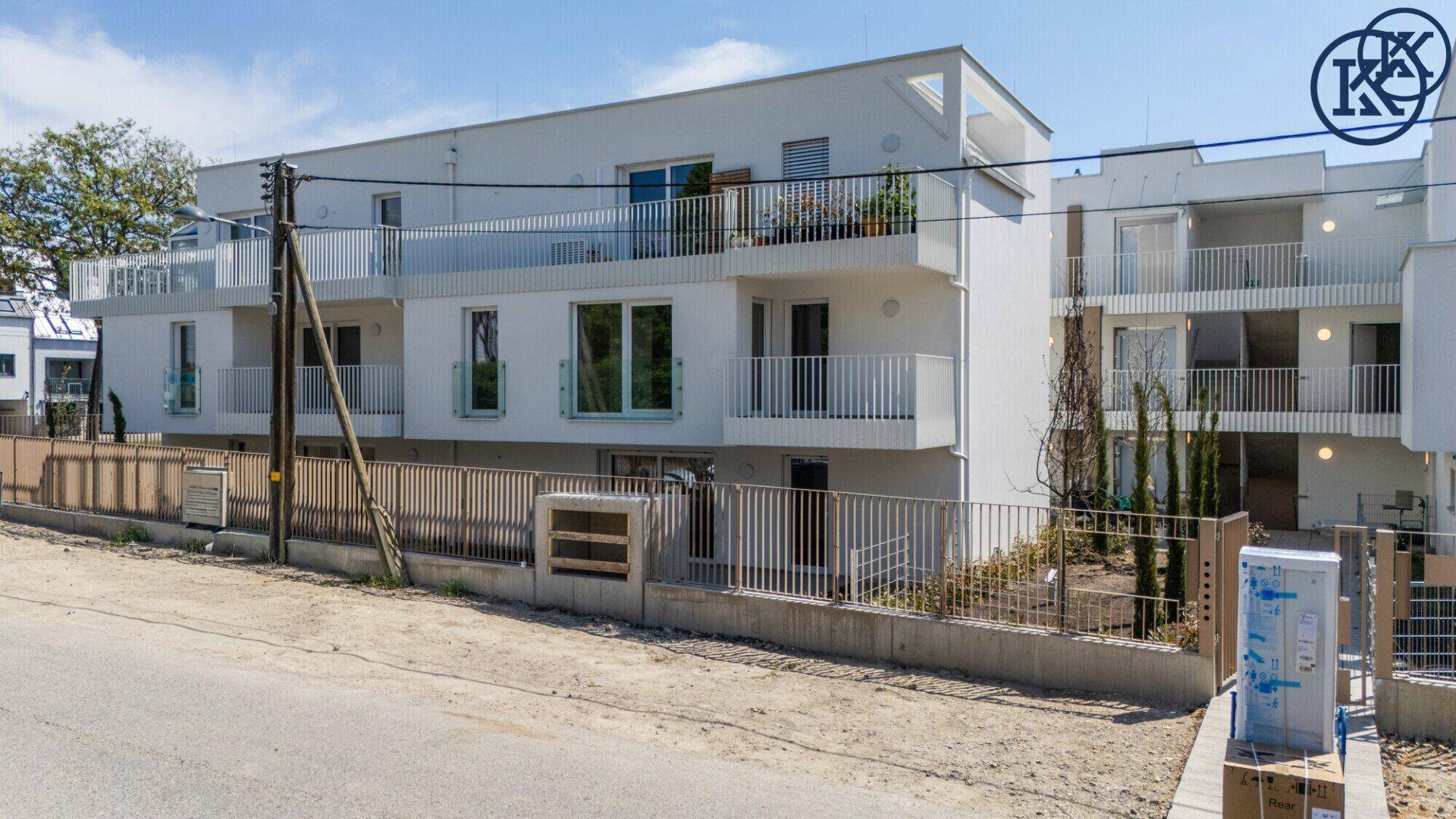 Moderne Wohnanlage mit weißer Fassade, Balkonen und großen Fenstern von oben betrachtet.