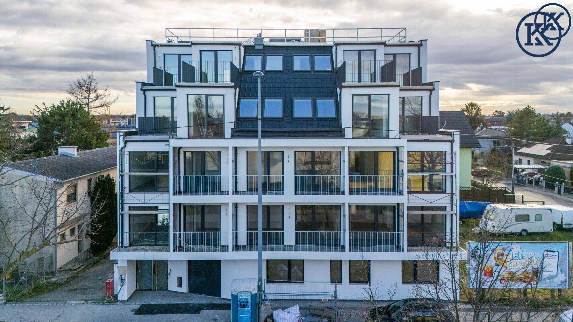 Modernes Wohnhaus mit mehreren Etagen, Balkonen und großen Fensterfronten.