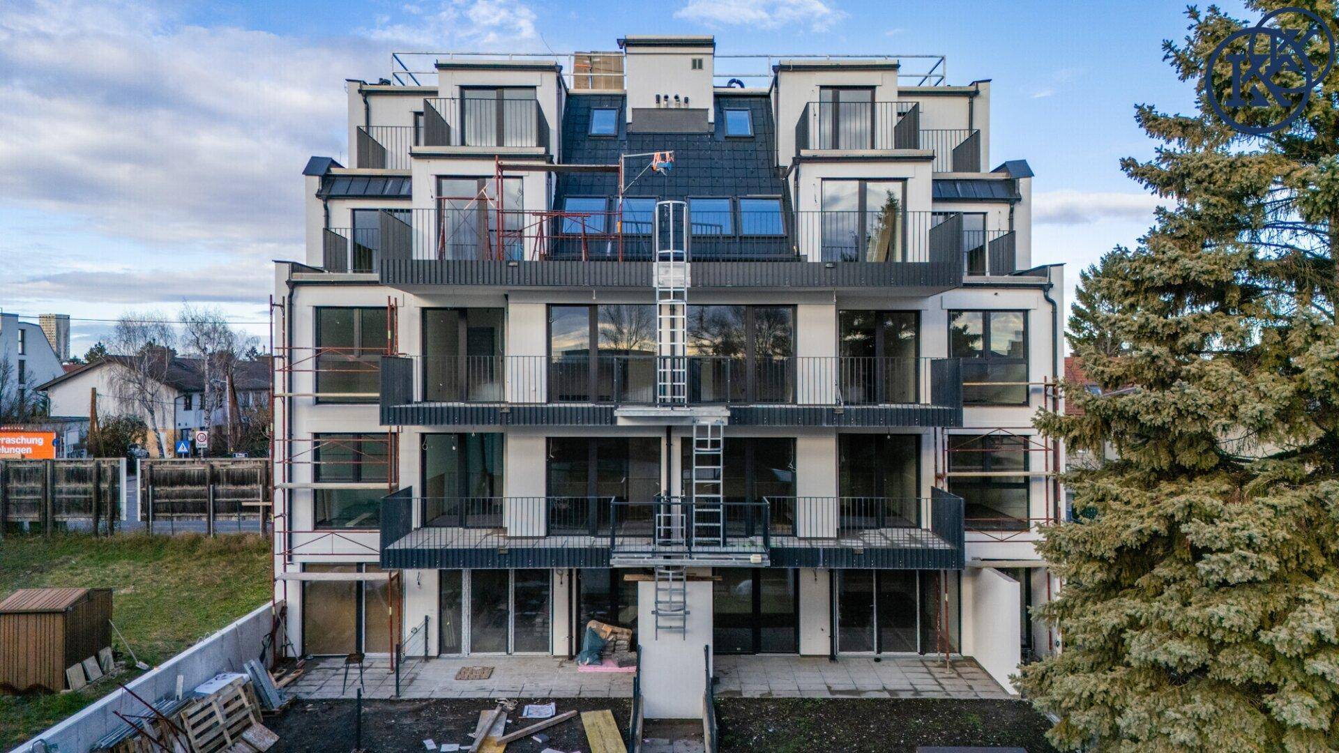 Rückansicht des modernen Wohngebäudes mit Balkonen, Terrassen und Gartenbereich.