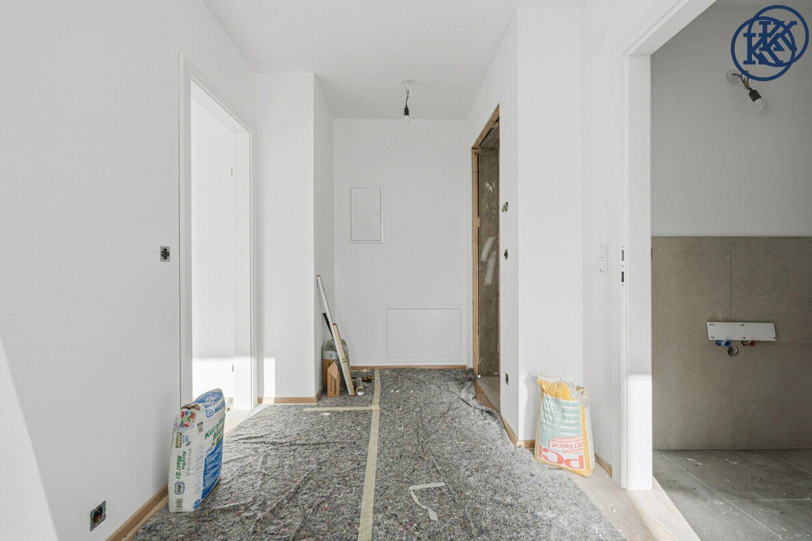 Flur oder Zimmer im Bau mit weiß gestrichenen Wänden und vorbereitetem Boden.