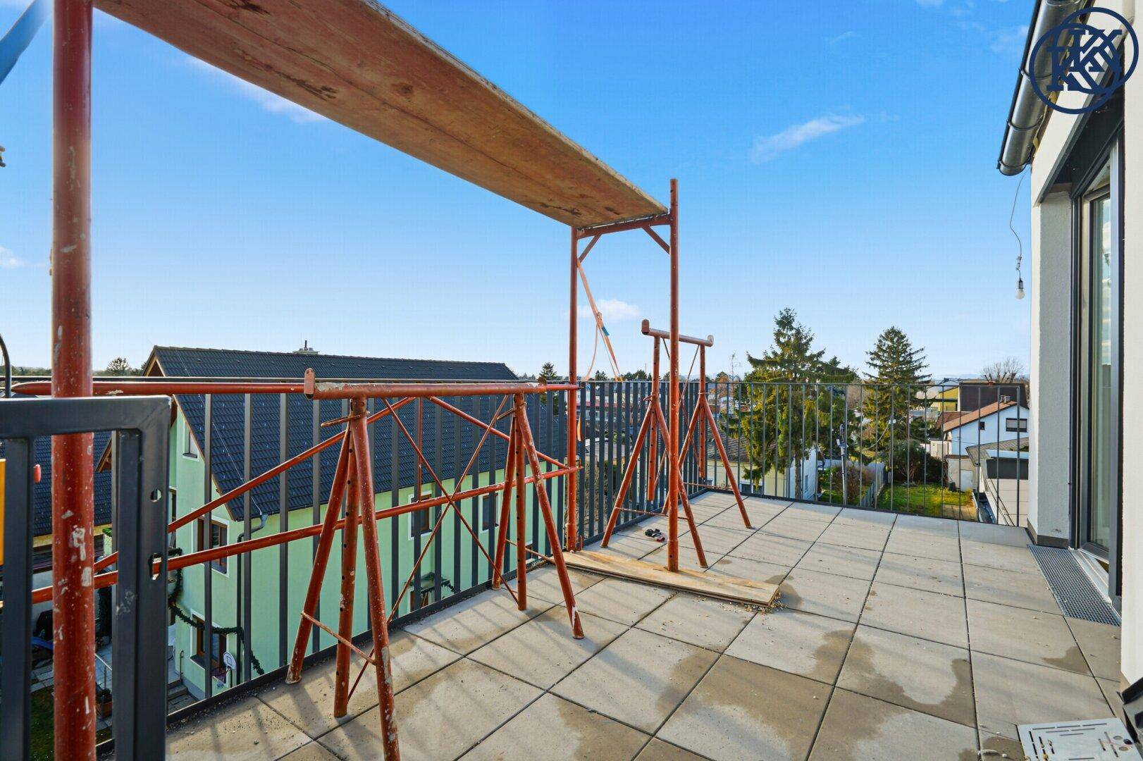 Helle Terrasse im Bau mit Fliesenboden und weitem Blick über die Dächer.