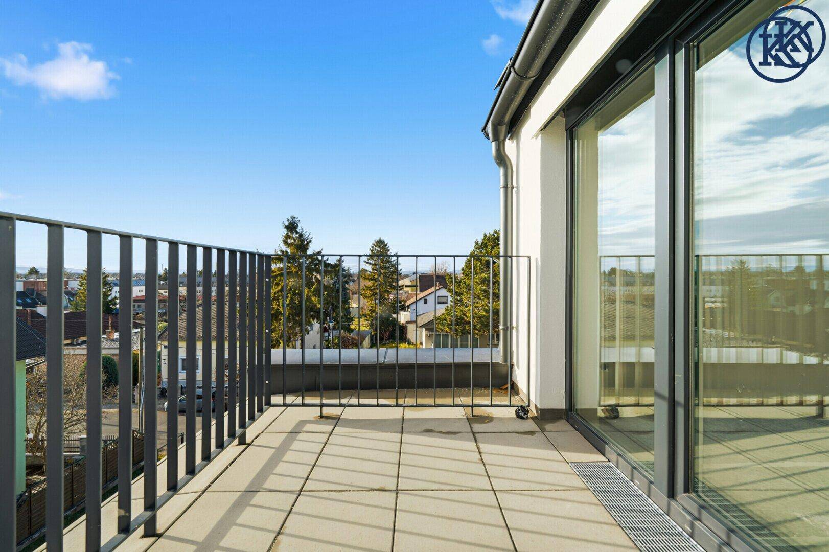 Geräumiger Balkon mit Fliesenboden und Metallgeländer, bietet einen weiten Blick.