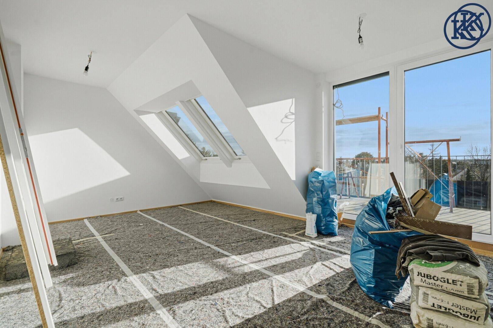 Dachgeschosszimmer im Bau mit schrägen Wänden, Dachfenstern und Zugang zu einem Balkon.