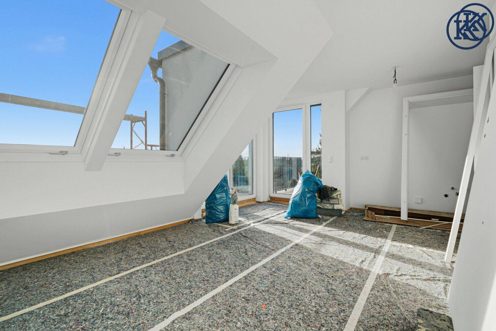 Helles Dachgeschosszimmer im Rohbau mit großen Dachfenstern und viel Tageslicht.
