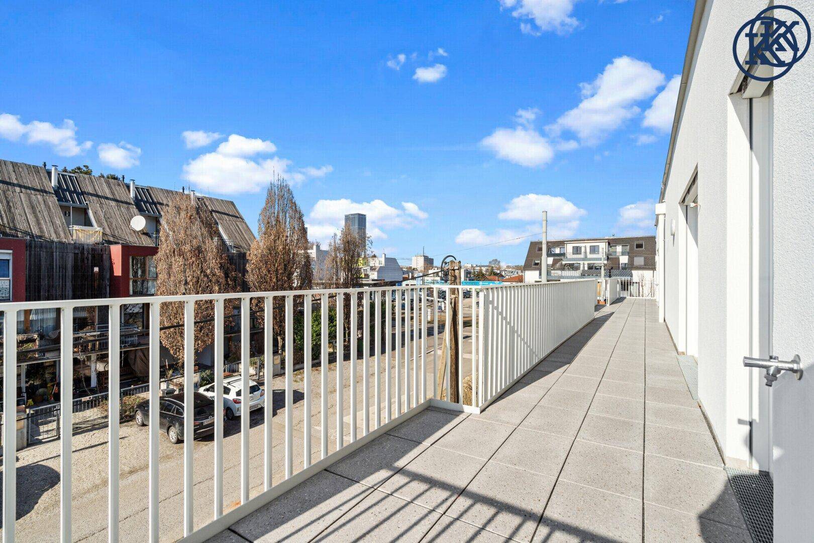 Geräumiger Balkon mit Fliesenboden, weißem Geländer und Blick auf die Straße.
