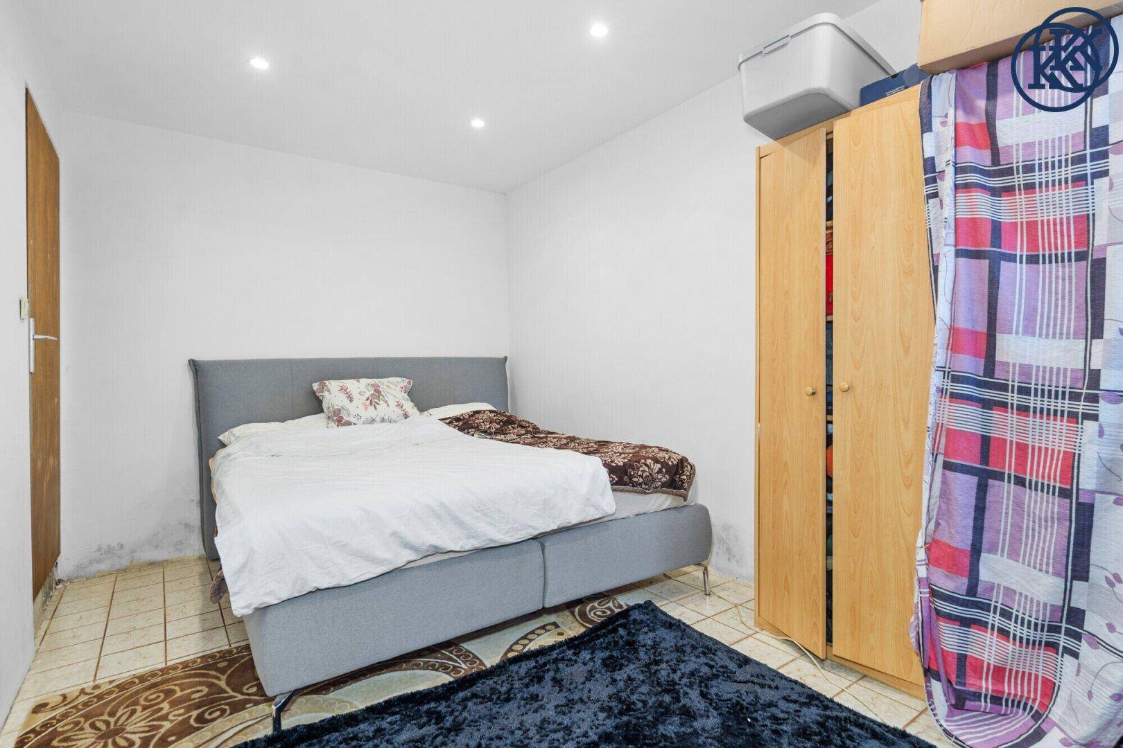Schlafzimmer mit Doppelbett, Kleiderschrank und Fliesenboden.