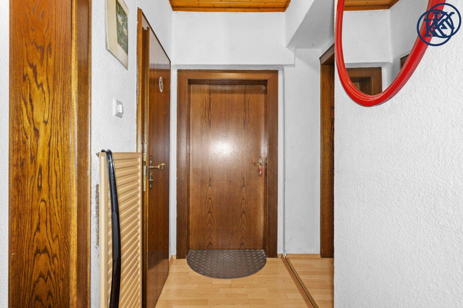 Eingangsbereich mit Holztüren, Holzdecke und einem Spiegel an der weißen Wand.