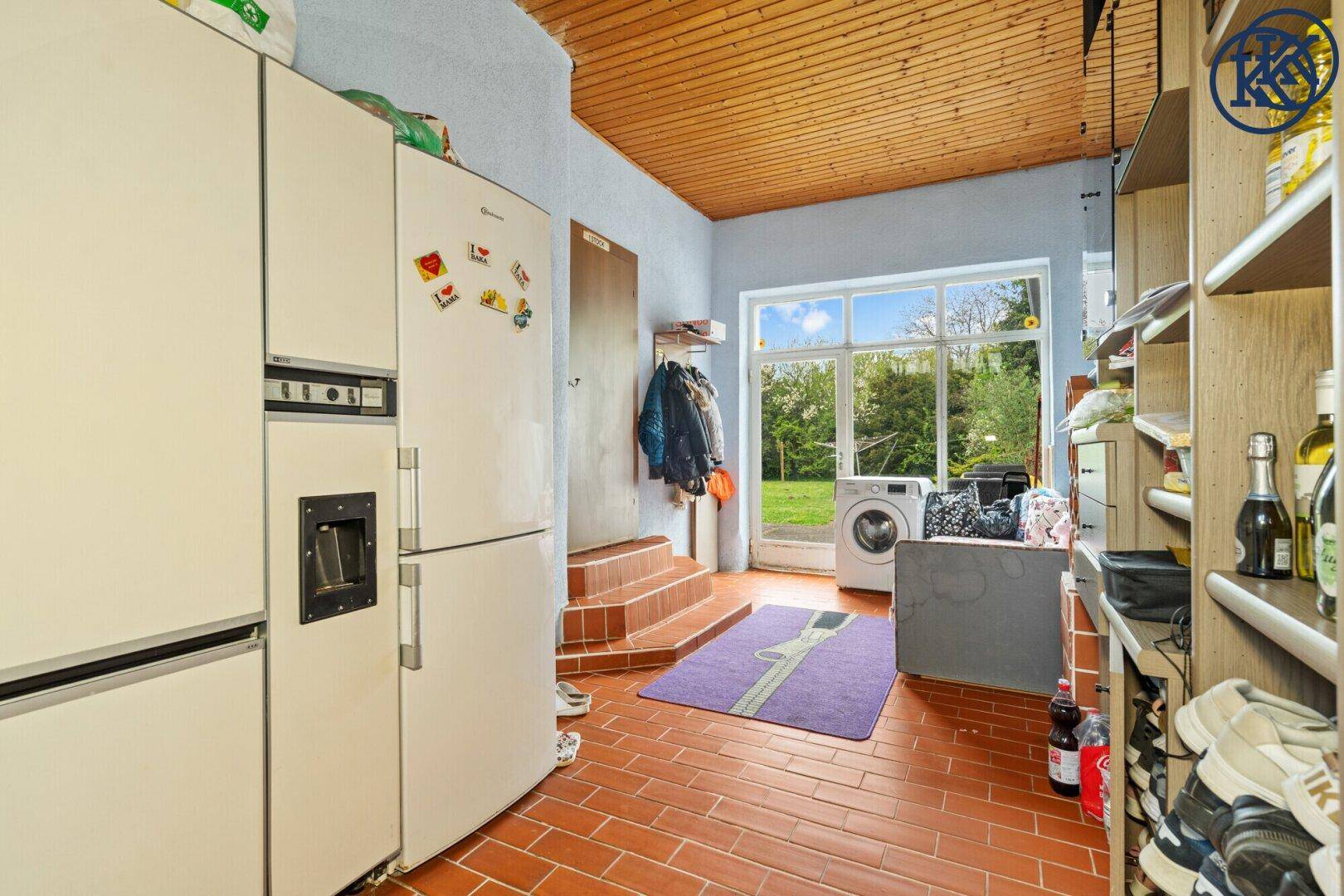 Hauswirtschaftsraum mit Kühlschrank, Regalen und Zugang zum Garten.
