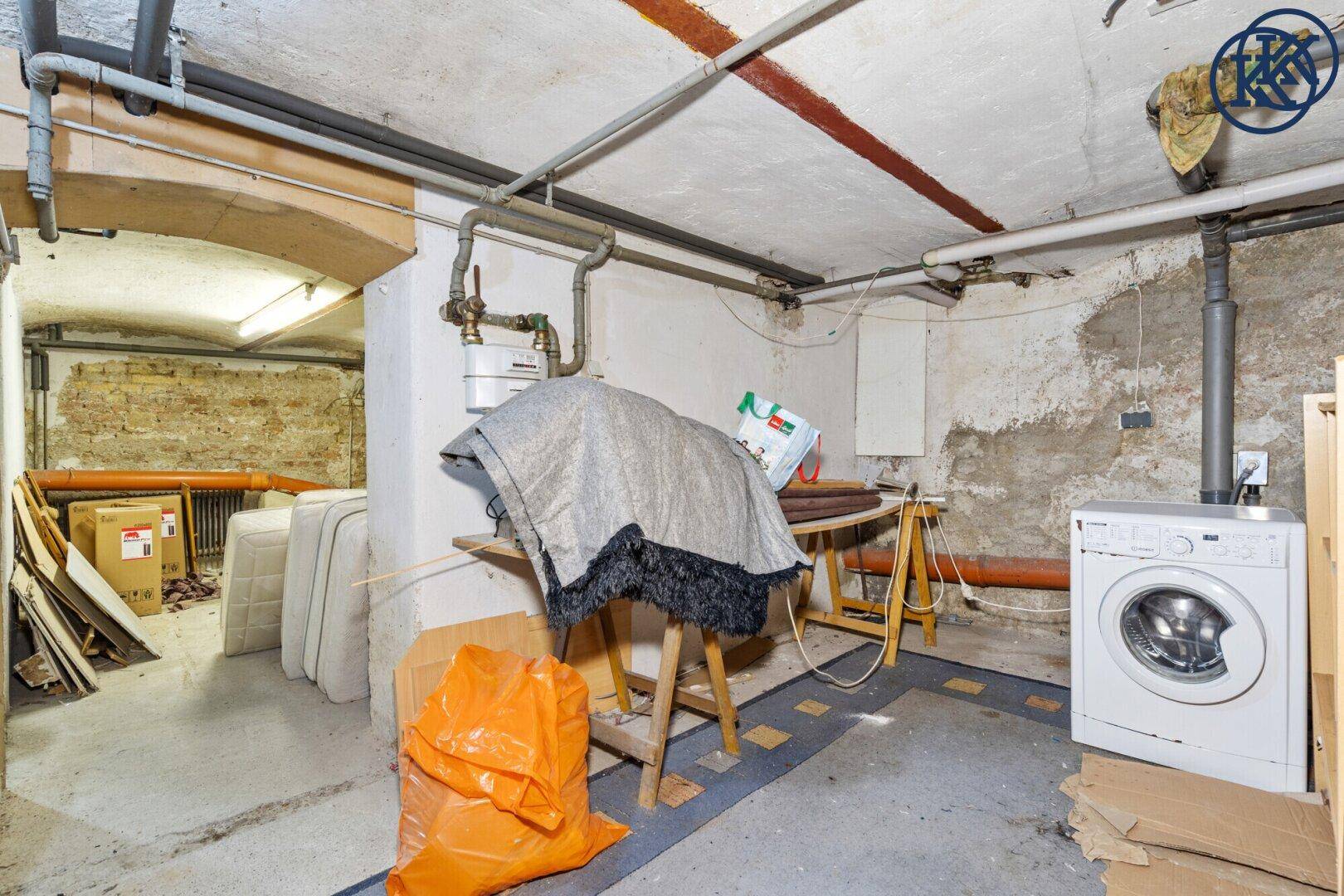 Unausgebauter Kellerraum mit Waschmaschine, Rohren und unverputzten Wänden.