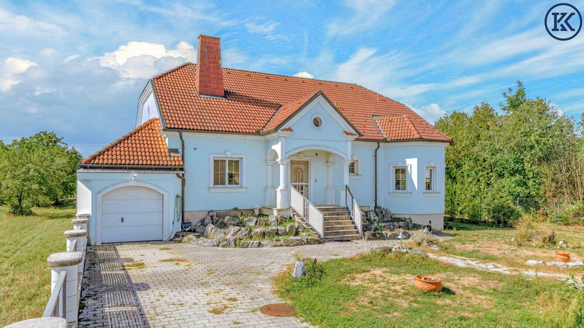 Seitenansicht des Hauses mit integrierter Garage, gepflasterter Zufahrt und Steingarten am Eingang.
