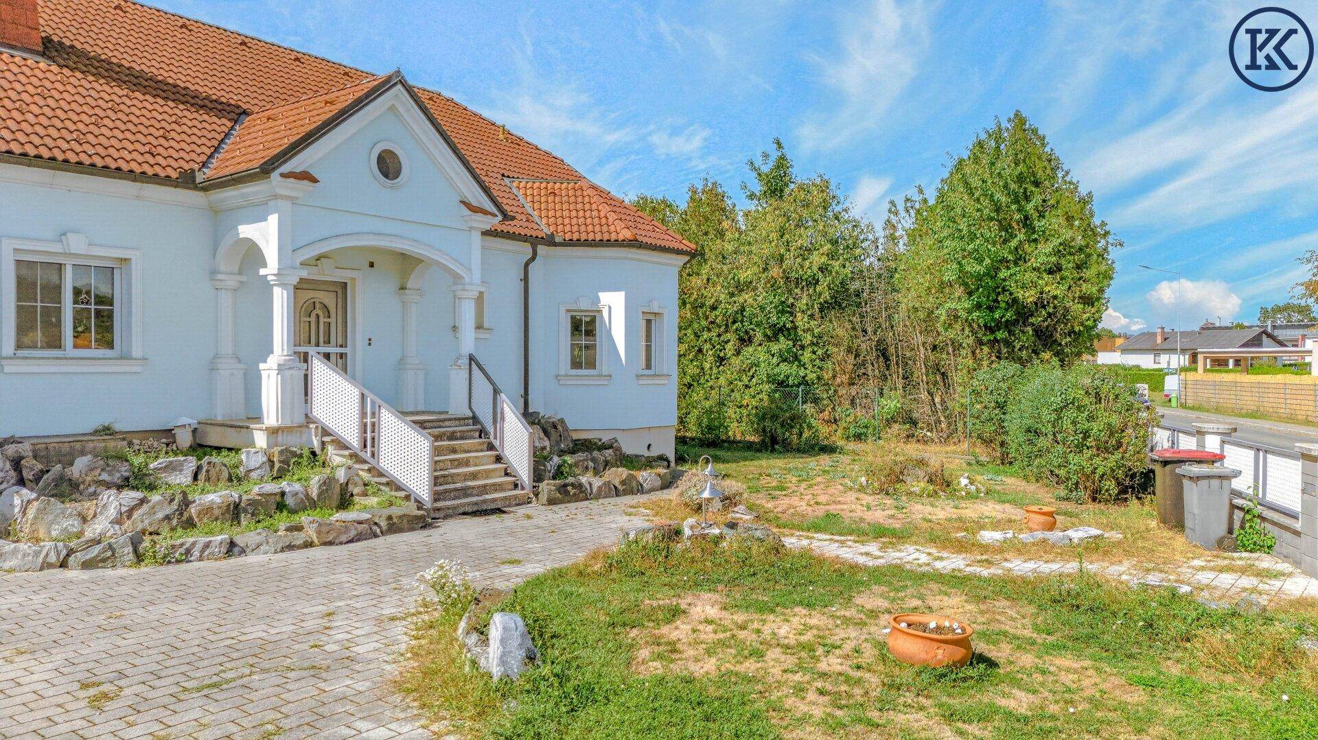 Eingangsbereich des Hauses mit Steintreppe, dekorativen Felsen und einem kleinen Vorgarten.