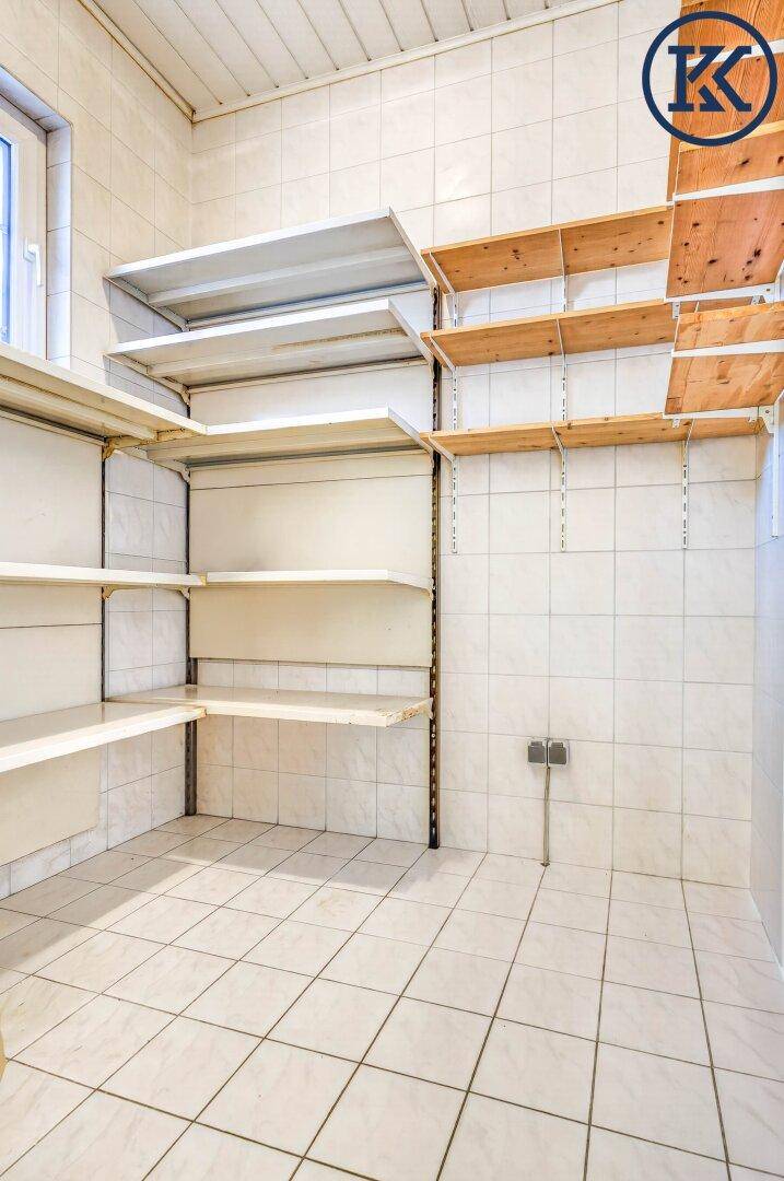 Gut organisierte Speisekammer mit gefliestem Boden und verschiedenen Regalsystemen für Lagerung.