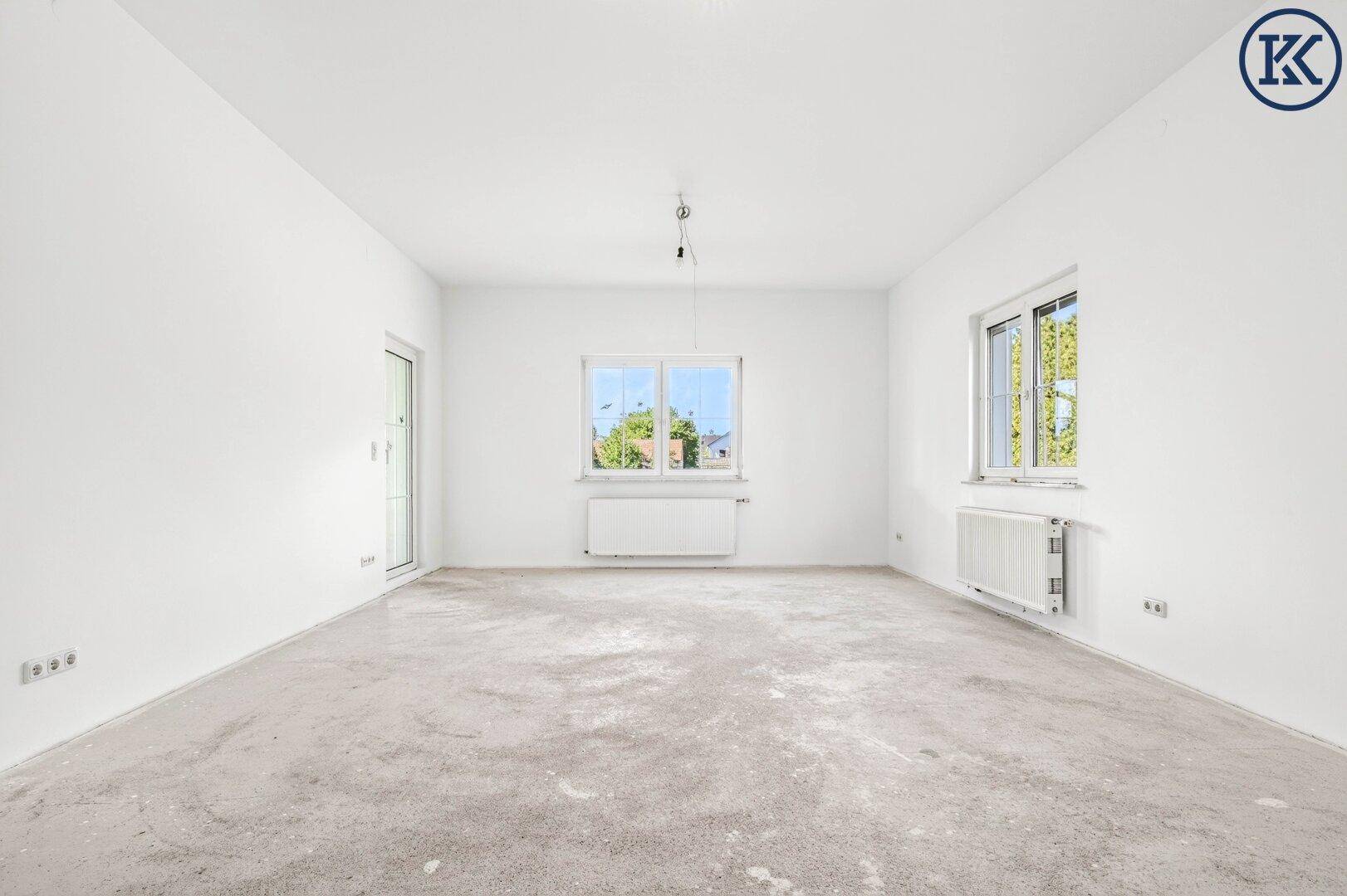 Leeres Wohnzimmer mit weißen Wänden, Rohbetonboden und großen Fenstern, bereit für die Gestaltung.