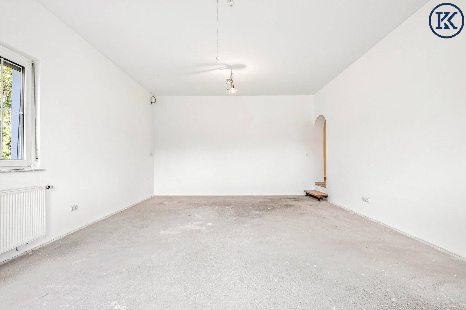 Geräumiges, unmöbliertes Wohnzimmer mit weißen Wänden und Betonboden, ideal für individuelle Einrichtung.