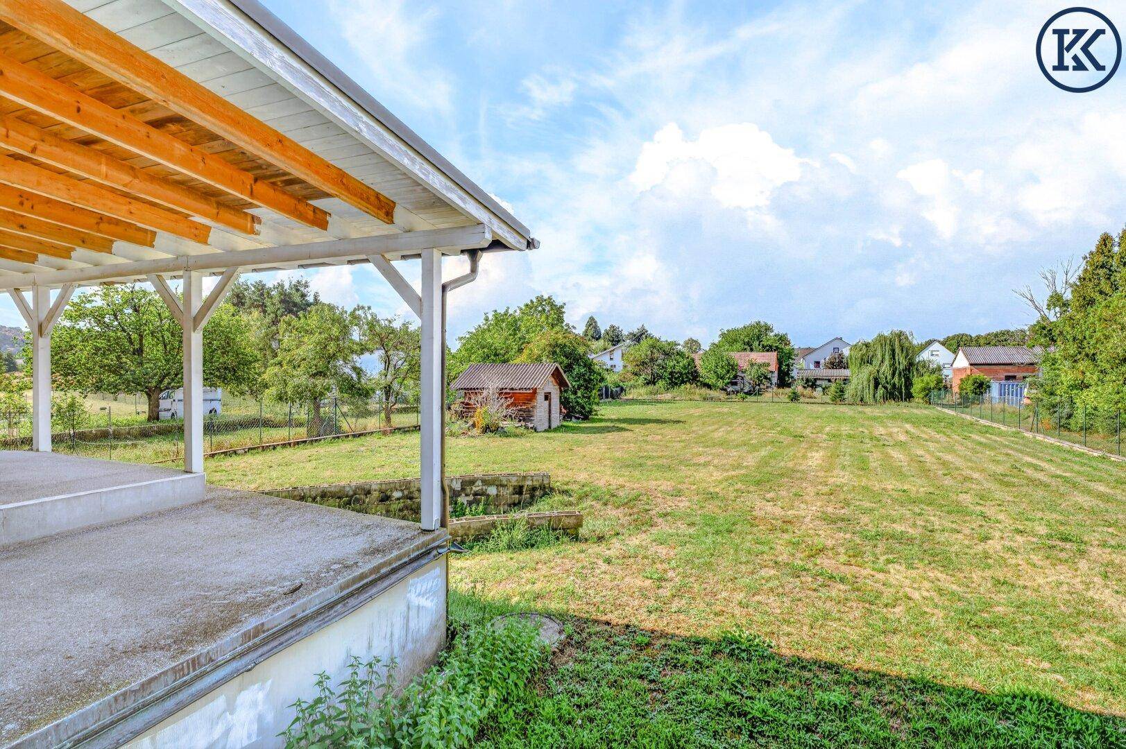 Großer, weitläufiger Garten mit Rasenfläche, Bäumen und einem kleinen Schuppen im Hintergrund.