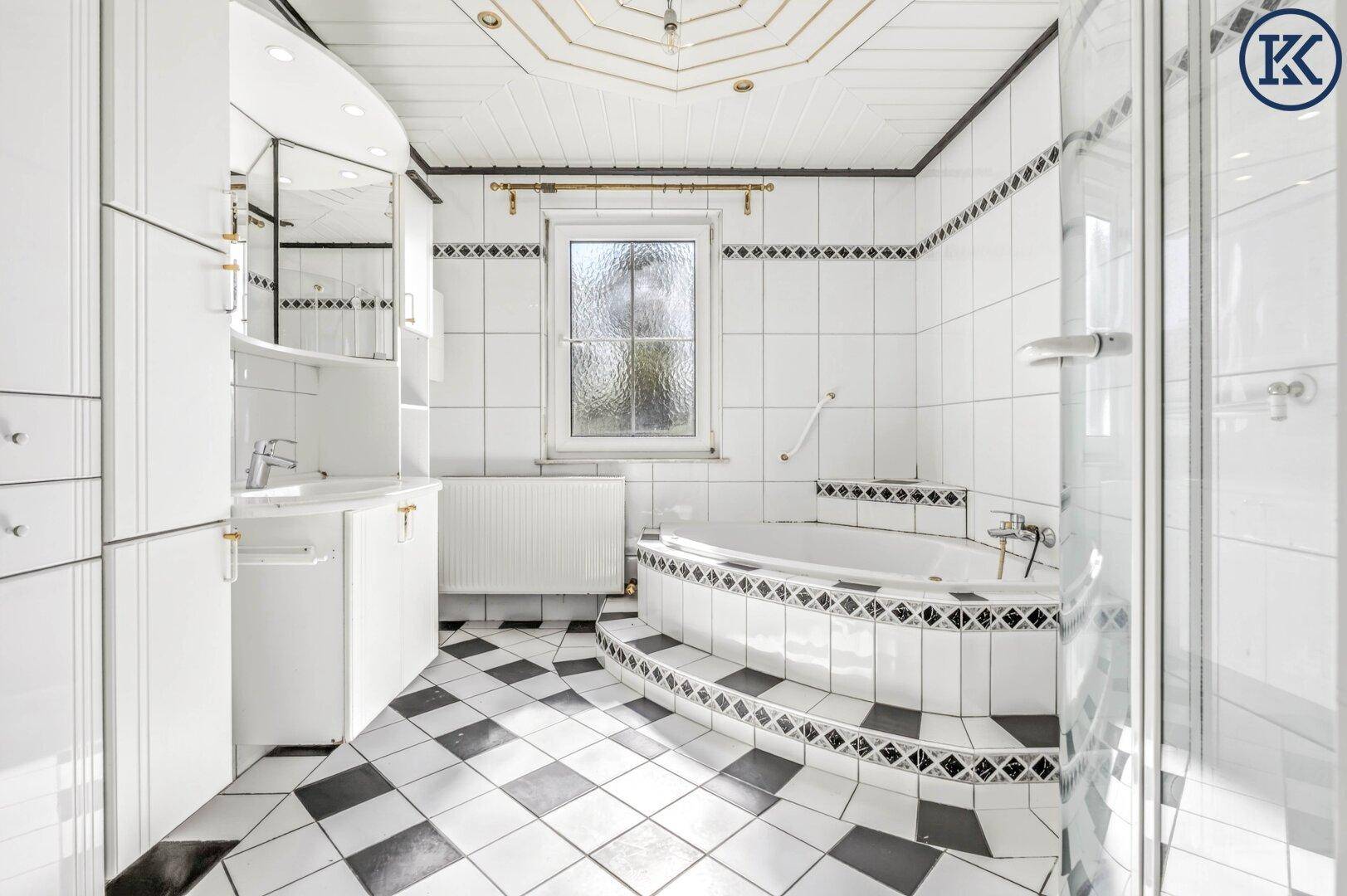 Geräumiges Badezimmer mit schwarz-weißem Fliesenmuster, Eckbadewanne und Duschkabine.