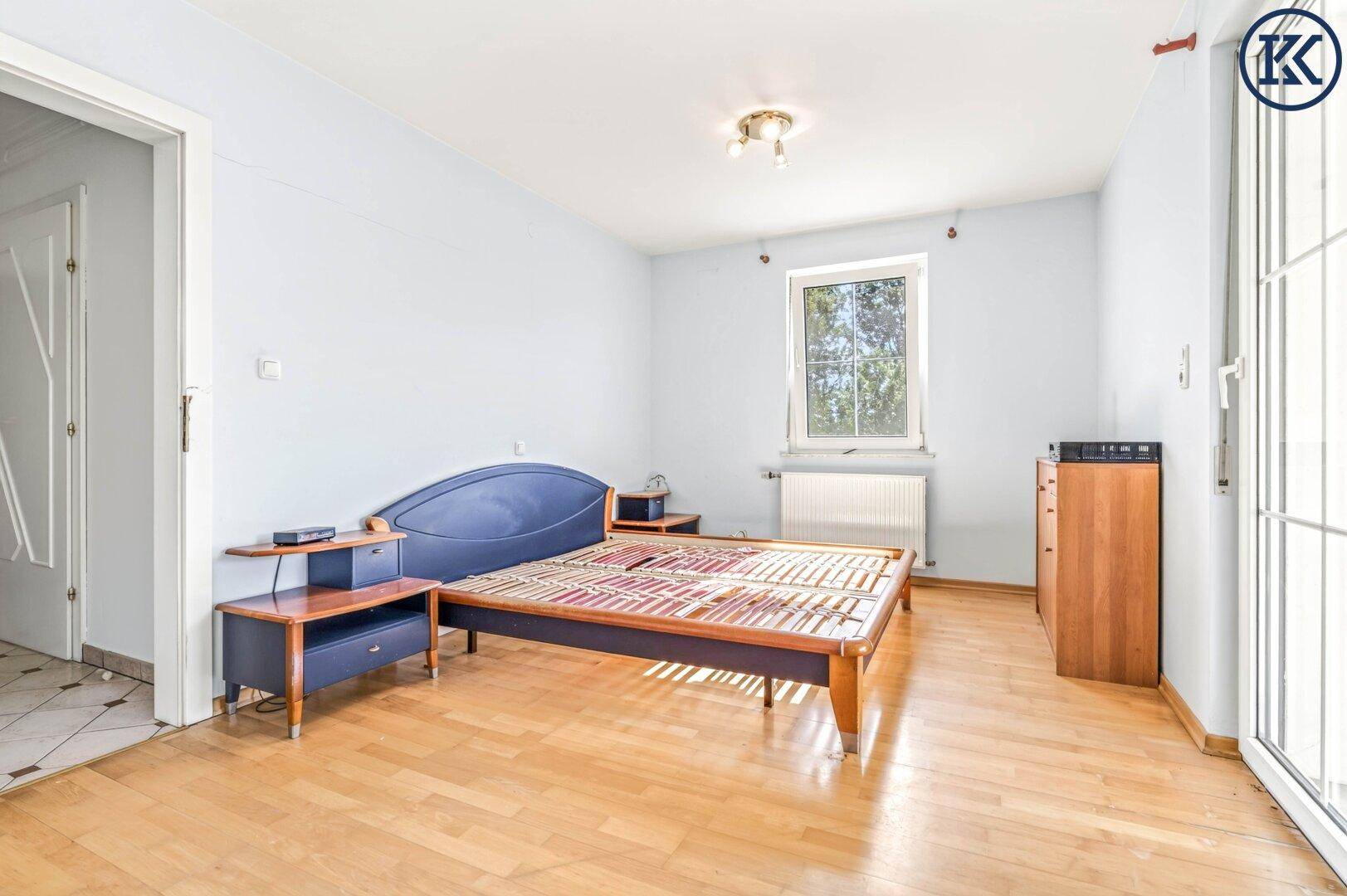 Schlafzimmer mit Holzboden, Fenster und einem Bettgestell, bereit zur Einrichtung.
