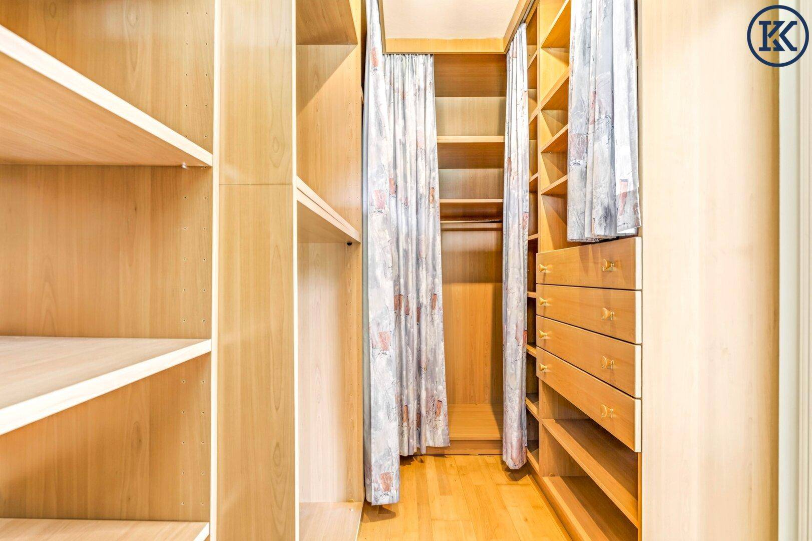 Geräumiger begehbarer Kleiderschrank mit Holzregalen und viel Stauraum für Kleidung.