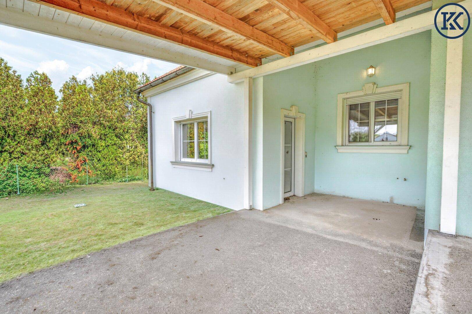 Überdachter Eingangsbereich oder Carport an der Seite des Hauses mit angrenzender Rasenfläche.