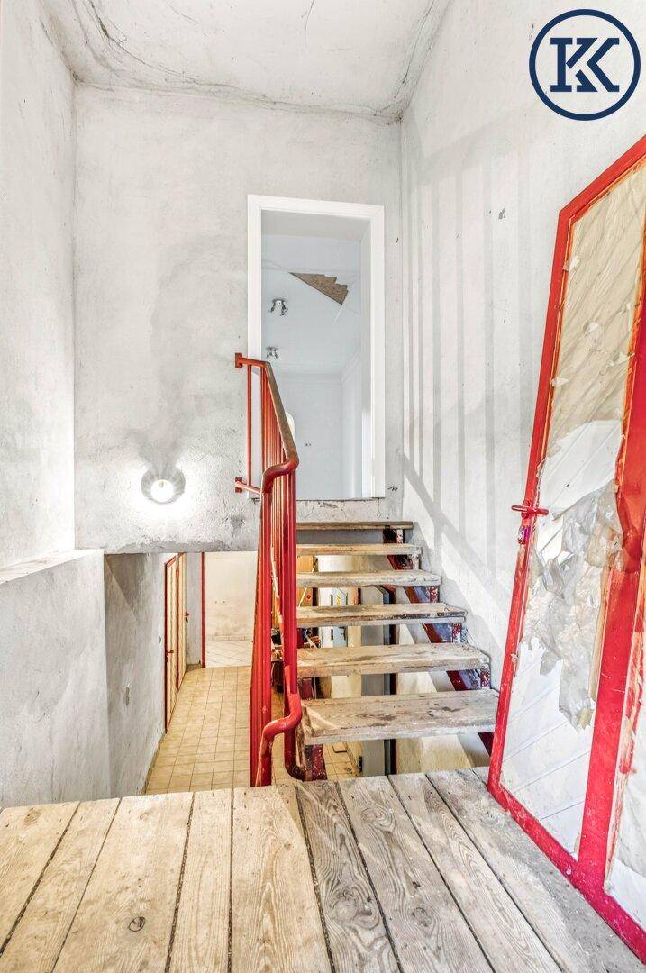 Blick auf die Kellertreppe mit rotem Geländer und rustikalen Holzstufen.