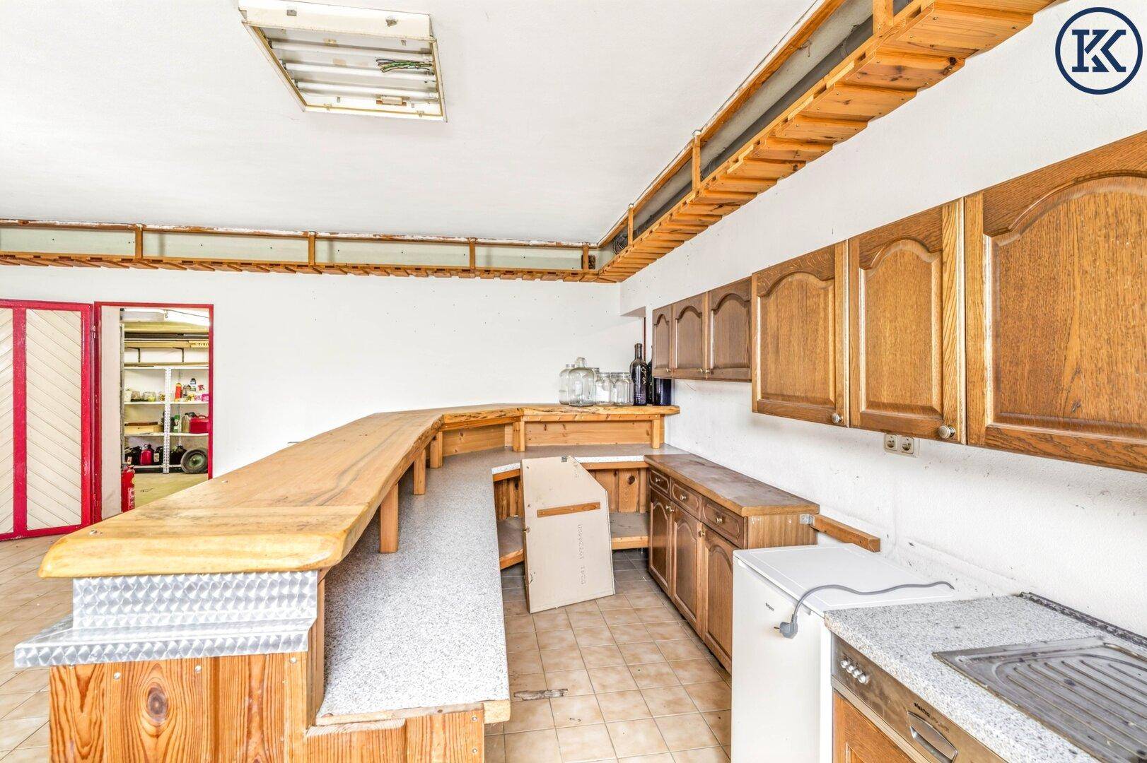 Langer Barbereich im Keller mit Holztheke und Zugang zu einem weiteren Raum.