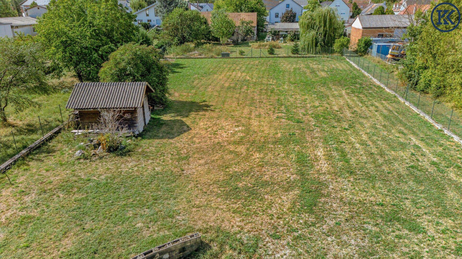 Weitläufiges Gartengrundstück mit Rasenfläche, Zaun und einem kleinen Holzschuppen, ideal für Erholung.