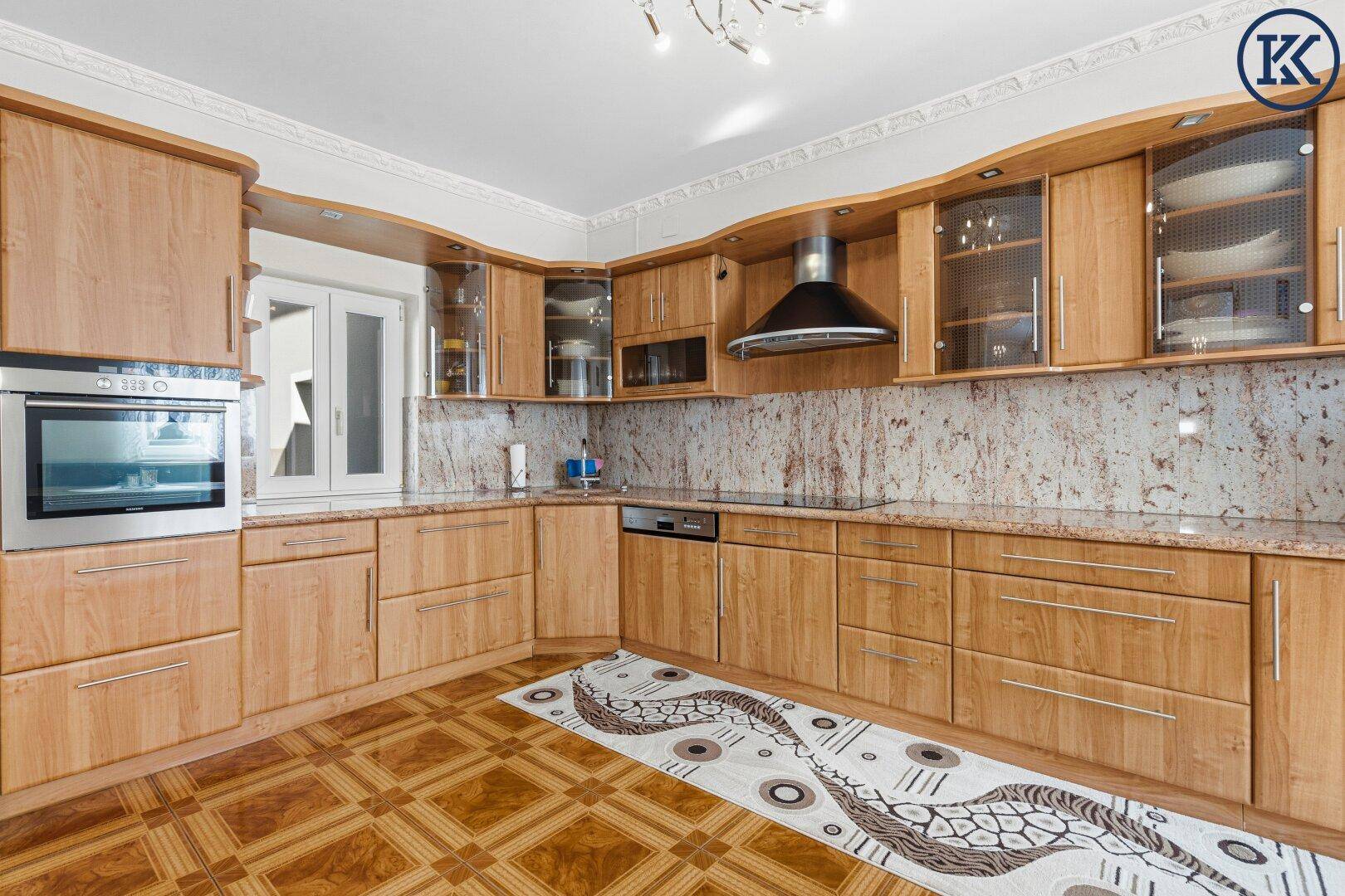 Geräumige Holzküche mit Granitarbeitsplatten, Einbaugeräten und Fliesenboden.