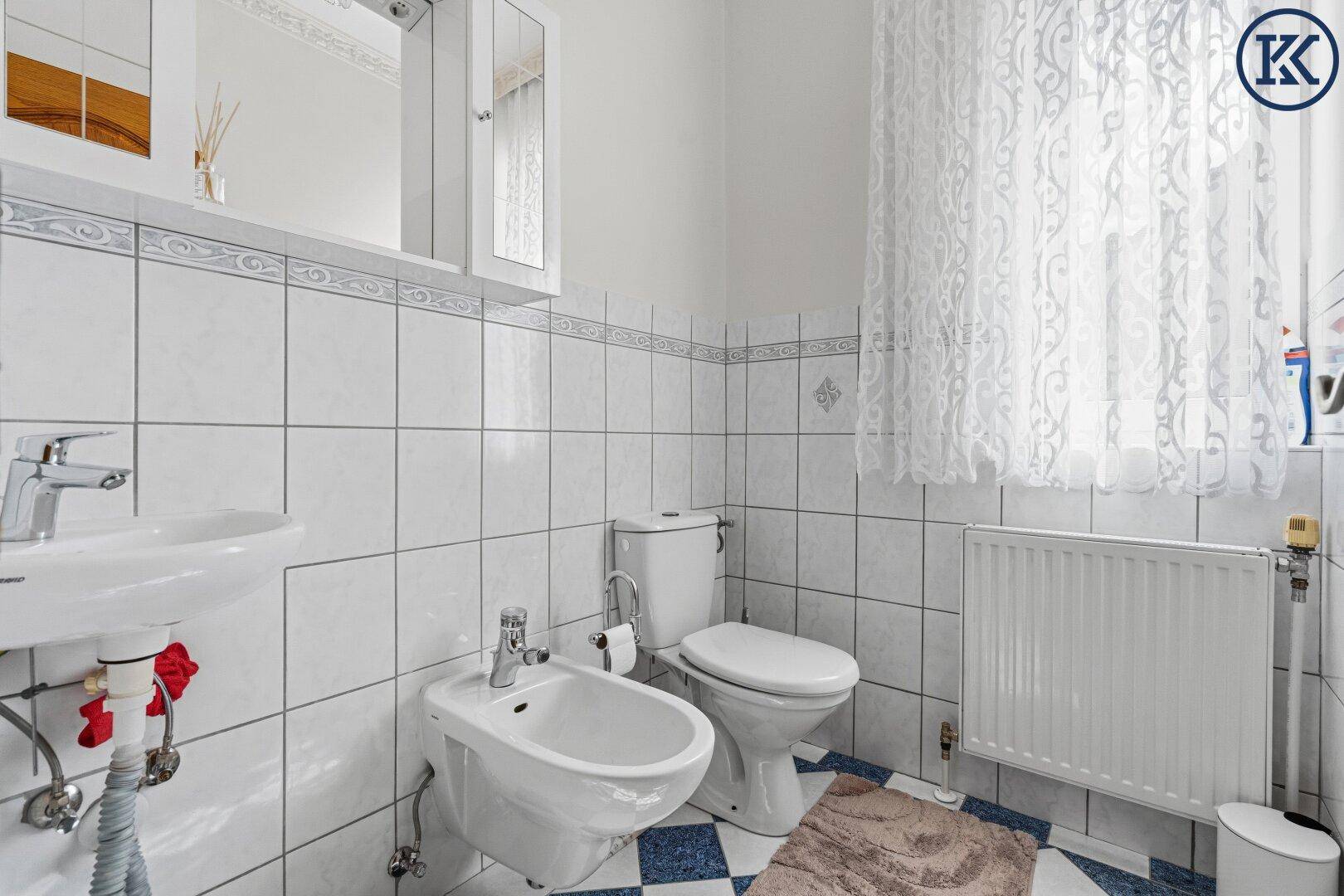 Kleines Gäste-WC mit weißen Fliesen, Bidet und Fenster für natürliche Belüftung.