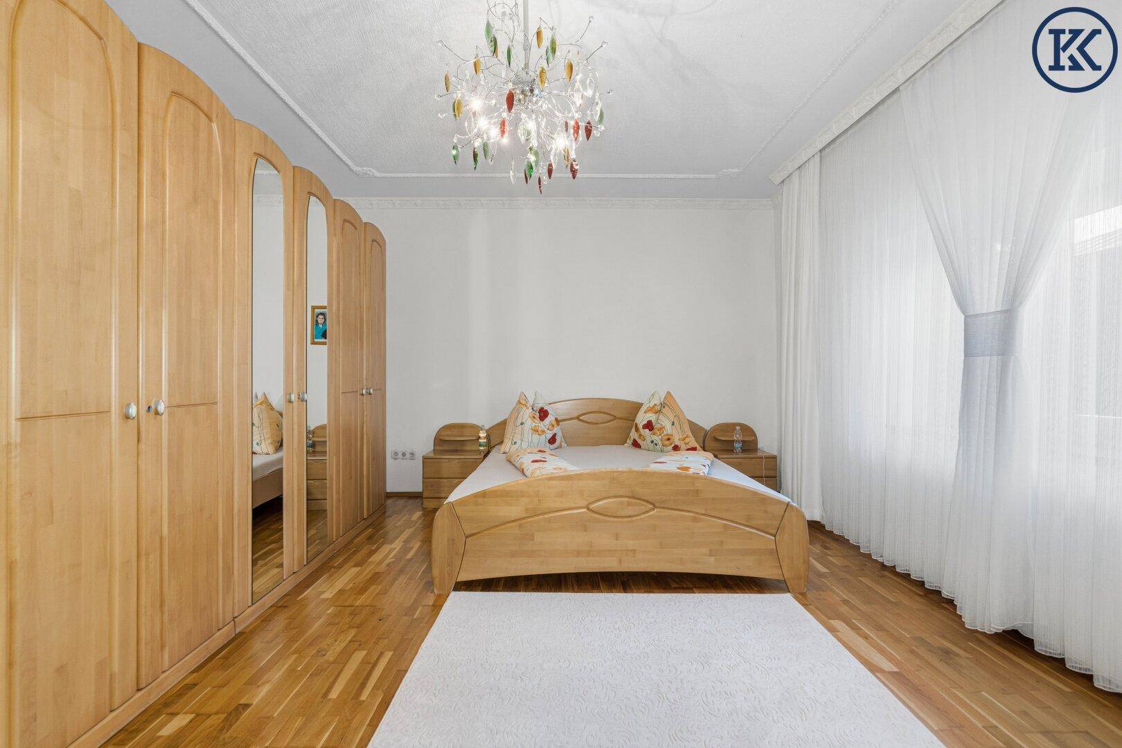 Helles Schlafzimmer mit Holzdoppelbett, großen Spiegelschränken und Parkettboden.