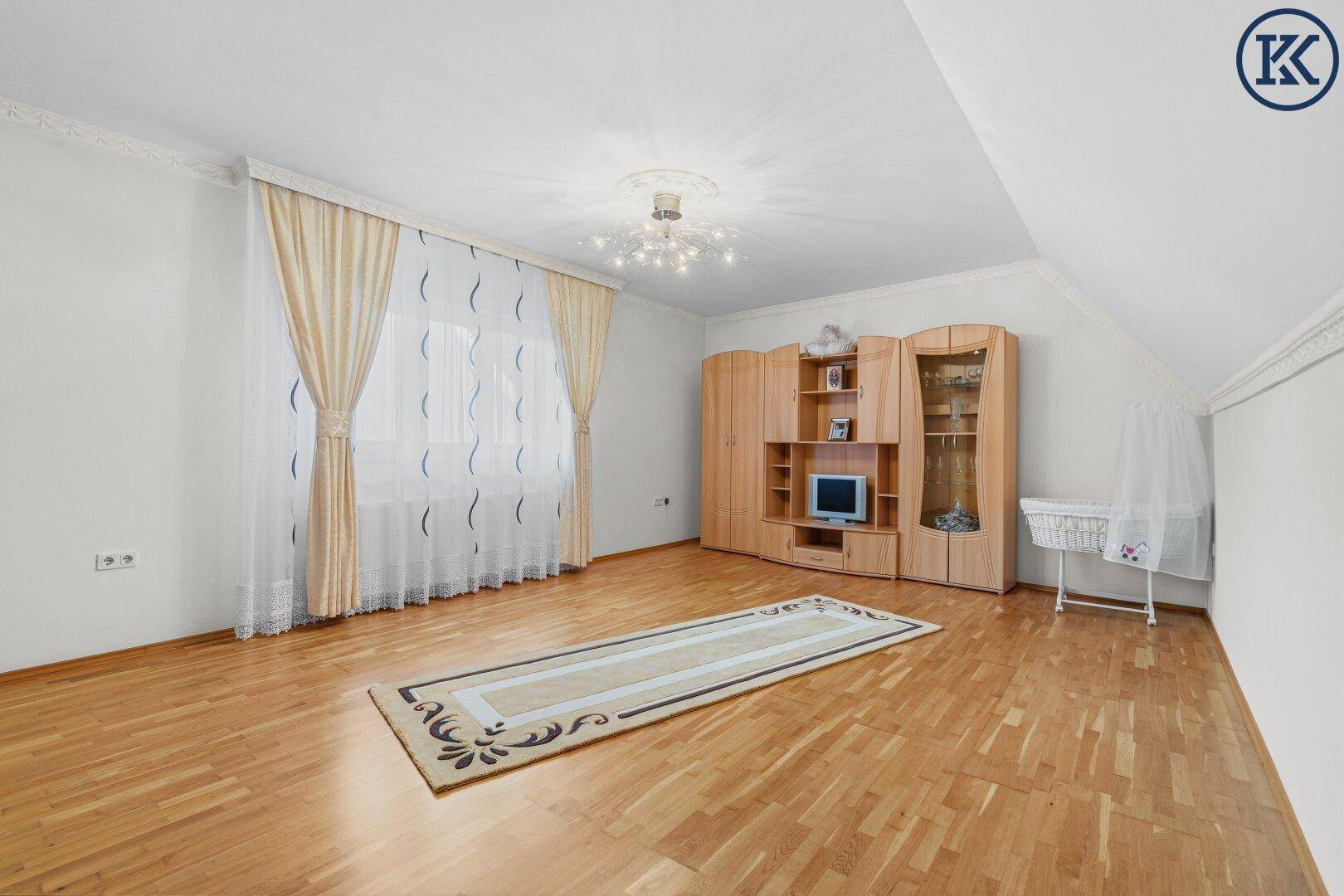 Helles Schlafzimmer mit Parkettboden, Dachschräge und großem Fenster.