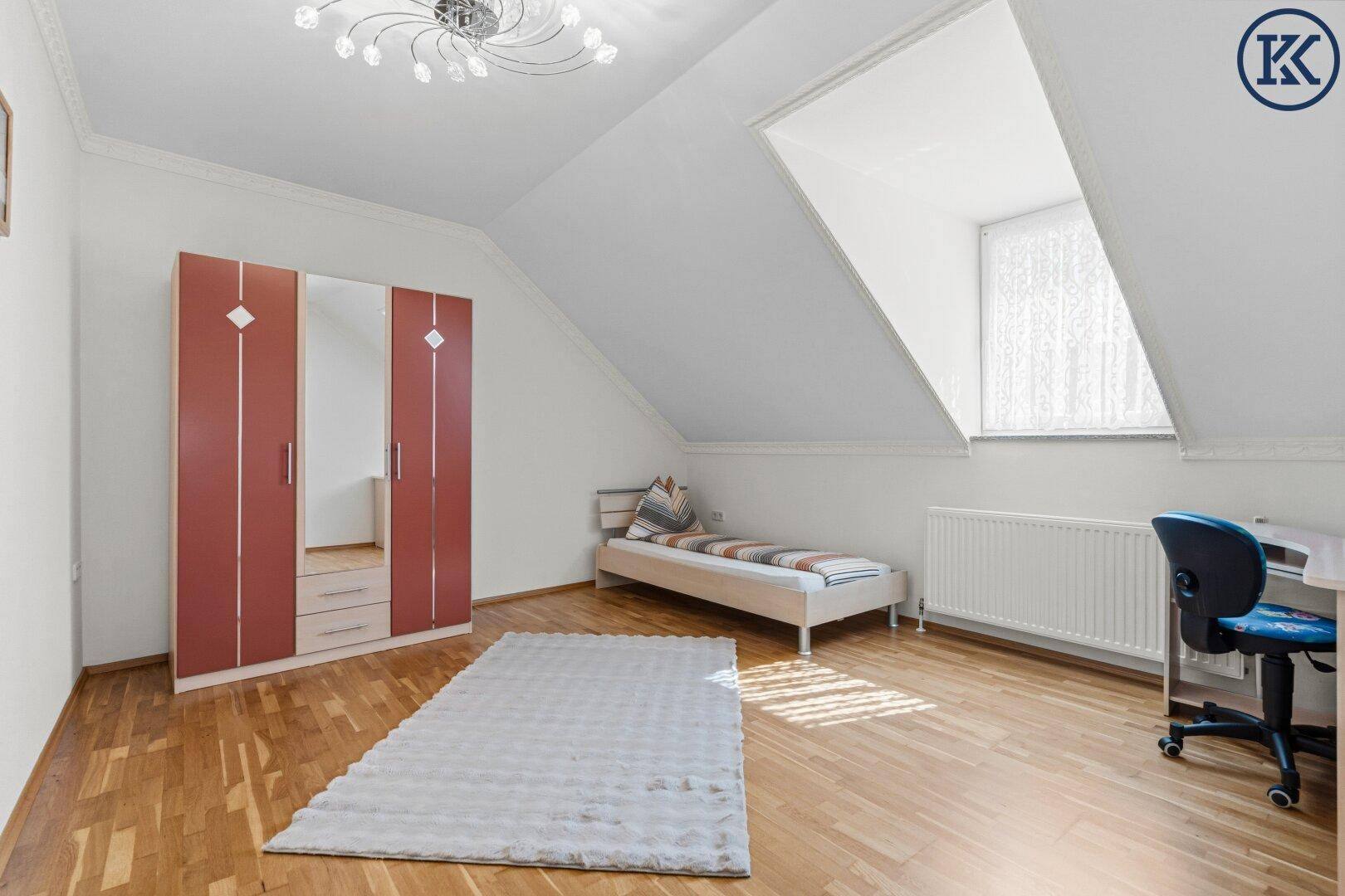 Kinderzimmer mit Parkettboden, Dachschräge und großem Dachfenster.