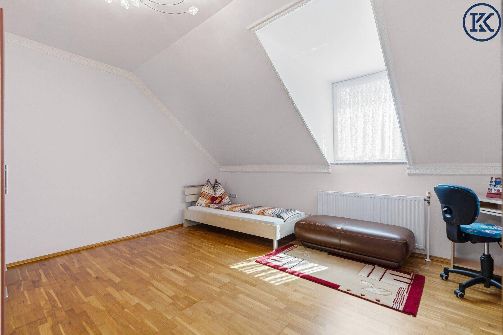 Kinderzimmer mit Parkettboden, Dachschräge und großem Dachfenster.