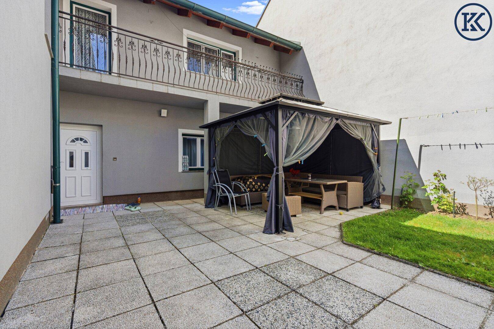 Gemütliche Gartenlaube auf der Terrasse mit Sitzgelegenheiten und Blick auf den Balkon.