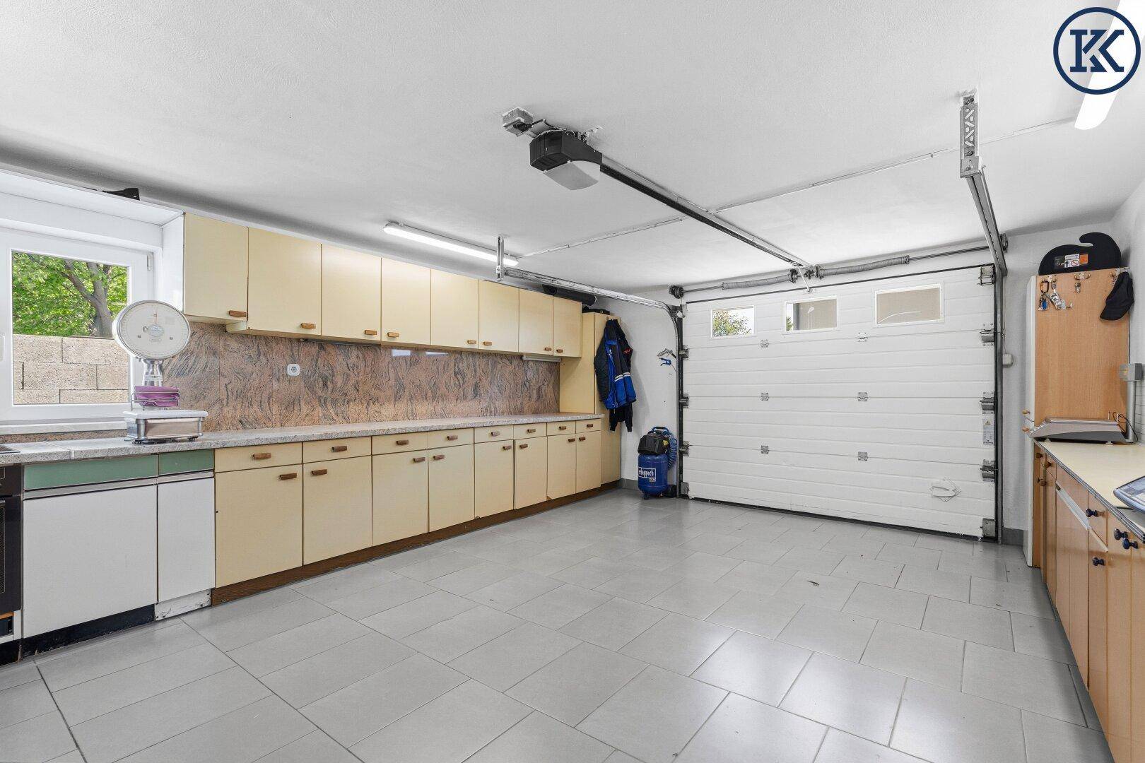 Geräumige Garage mit Sektionaltor, Fliesenboden und vielen Einbauschränken.