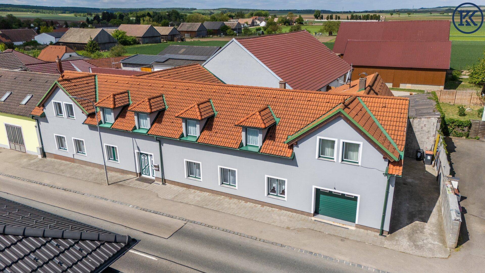 Weitläufige Luftaufnahme eines Wohnhauses mit rotem Ziegeldach und angrenzenden Feldern.