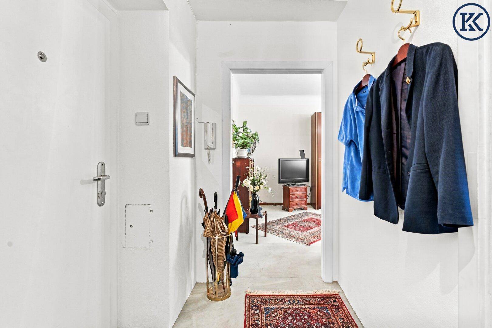 Heller Flur mit Garderobe, Teppichläufer und Blick in einen angrenzenden Raum.