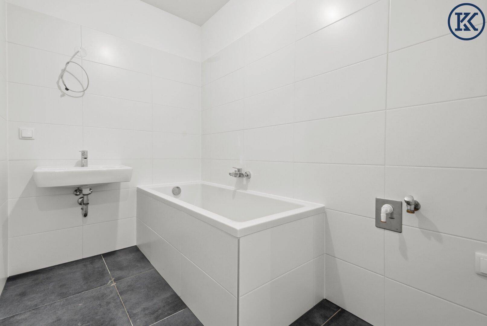 Modernes Badezimmer mit Badewanne, Waschbecken und weißen Fliesen an den Wänden.