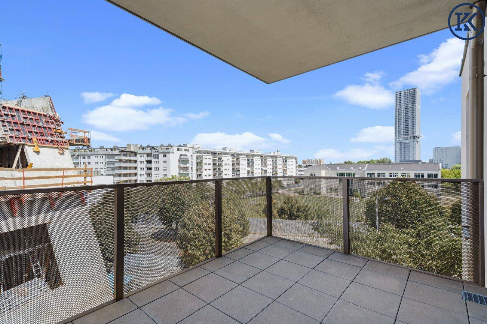 Großer Balkon mit Fliesenboden und Glasgeländer, bietet weiten Stadtblick.