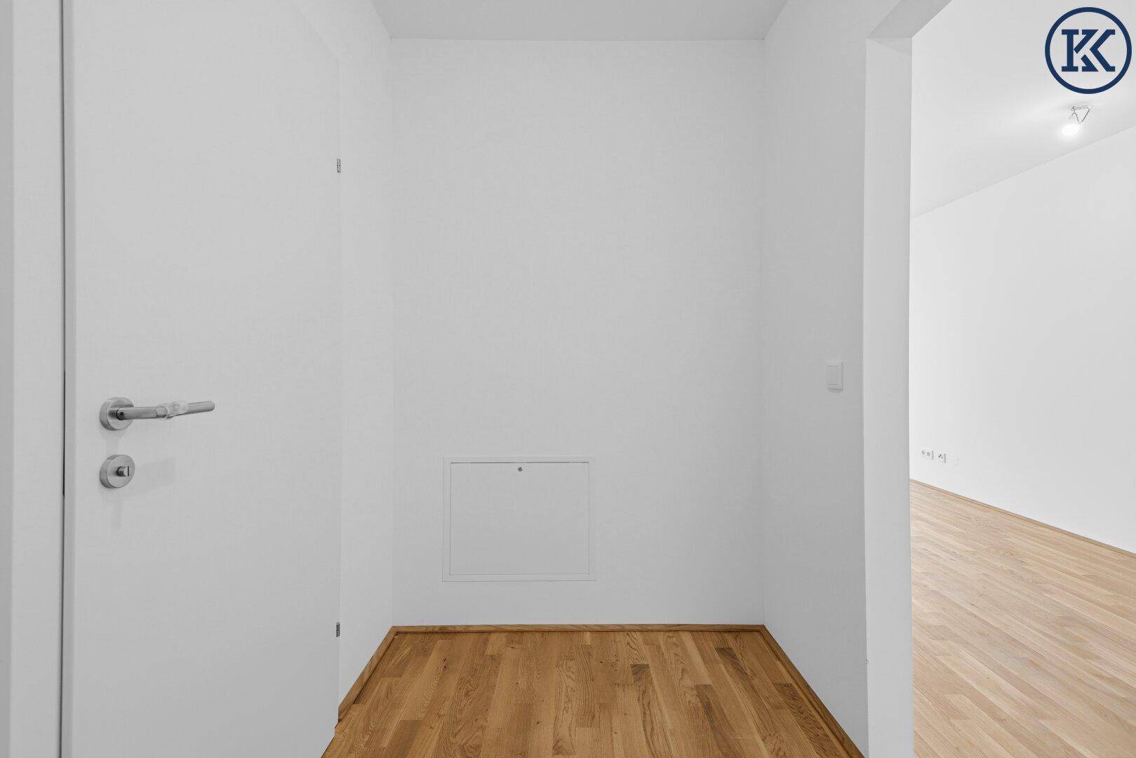 Heller Flur mit Holzboden und weiß gestrichenen Wänden, bereit zur individuellen Gestaltung.