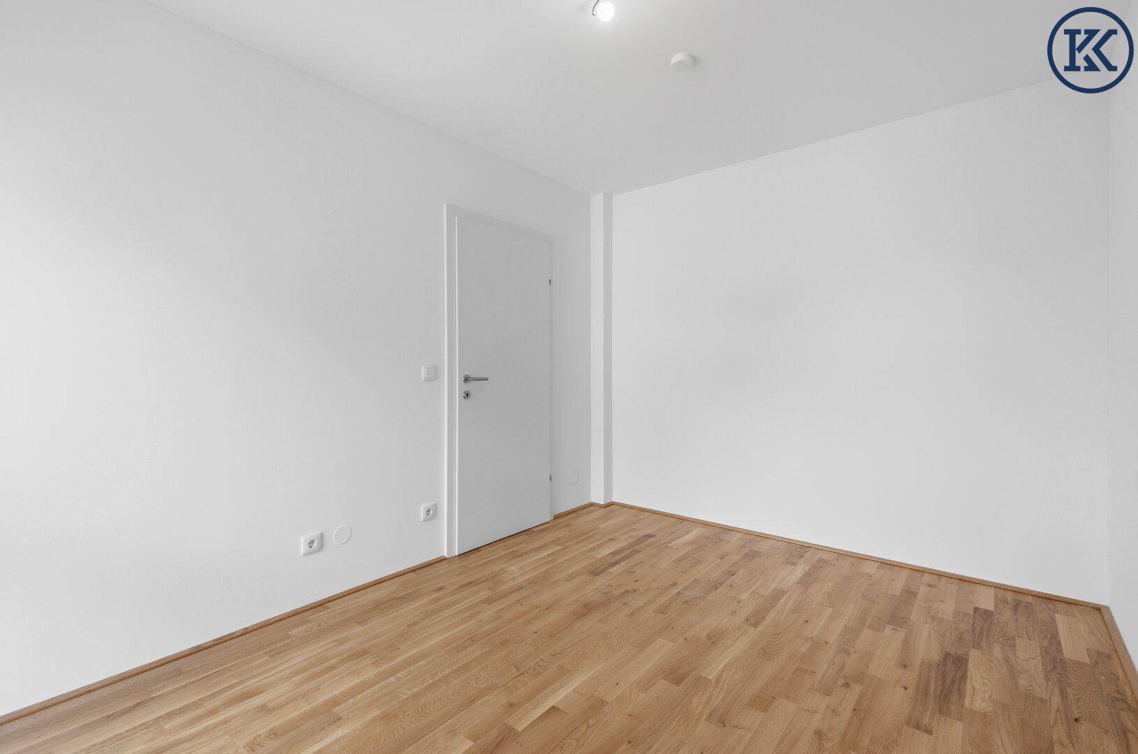 Geräumiges Schlafzimmer mit Parkettboden und weißer Tür, ideal für individuelle Gestaltung.