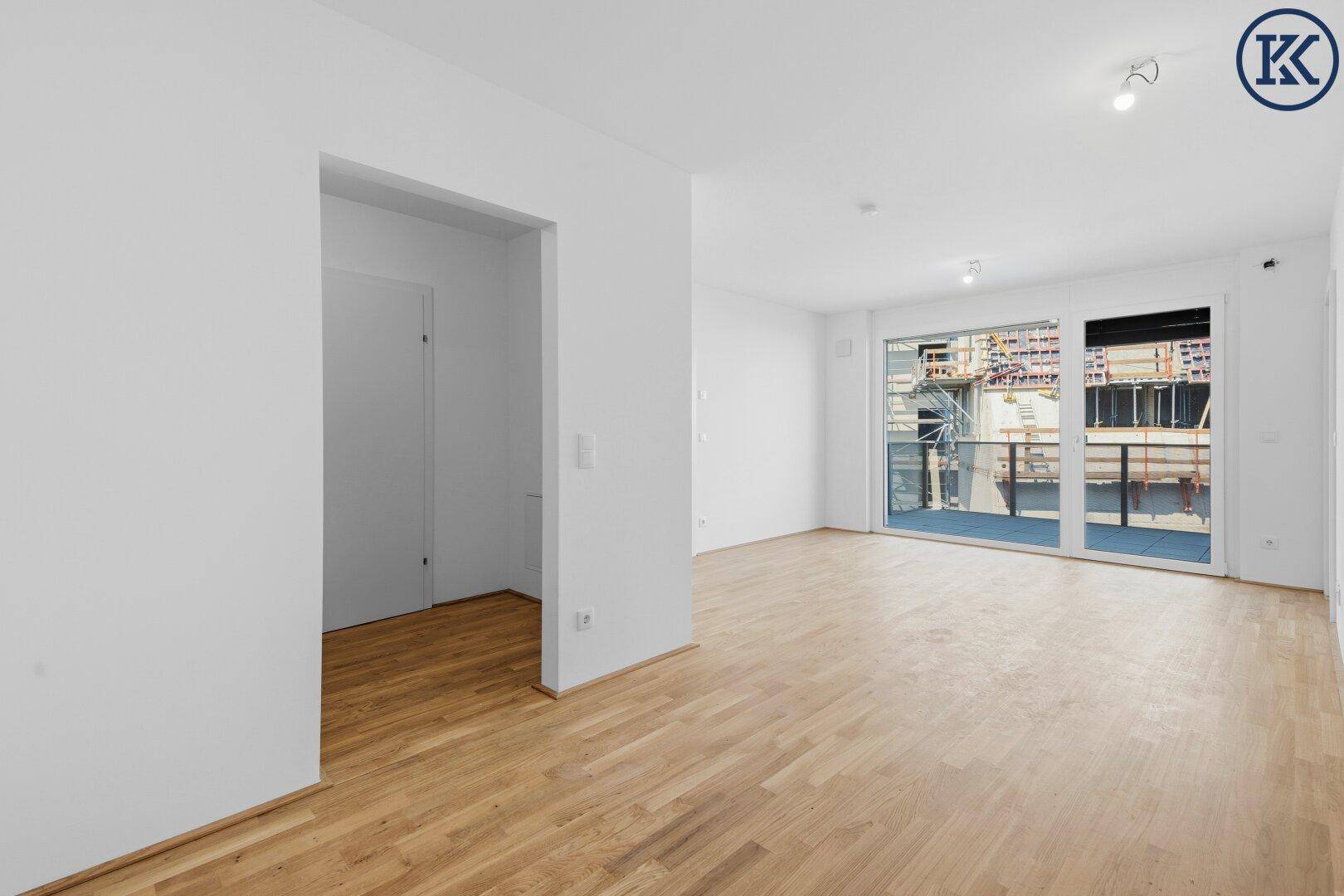 Geräumiges Wohnzimmer mit Holzboden und Zugang zu einem Balkon, derzeit im Bau.
