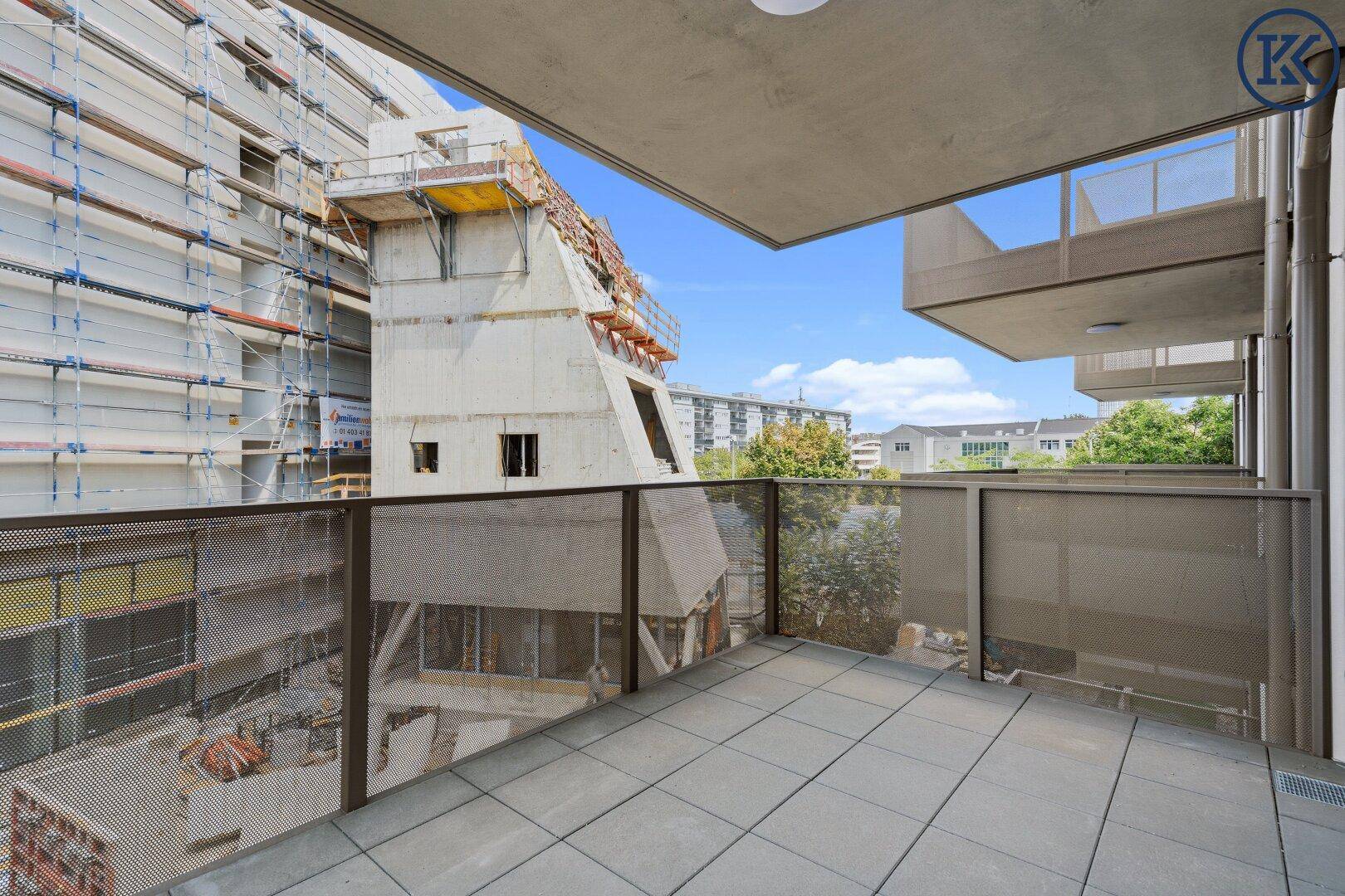 Balkon mit Fliesenboden und Blick auf die umliegende Baustelle und den Himmel.